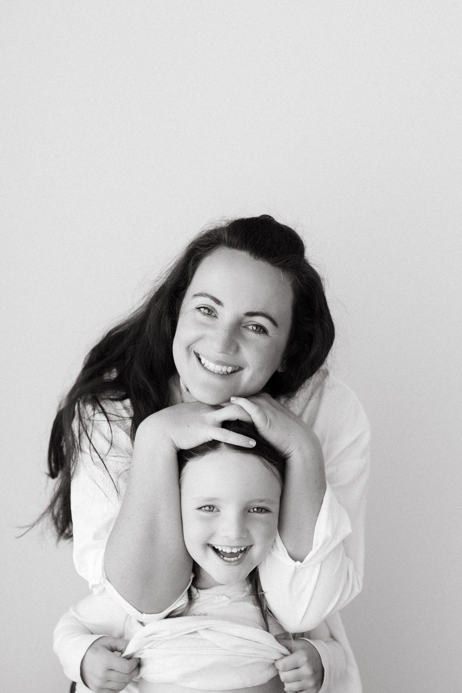 A playful black and white studio portrait showing genuine laughter and connection.