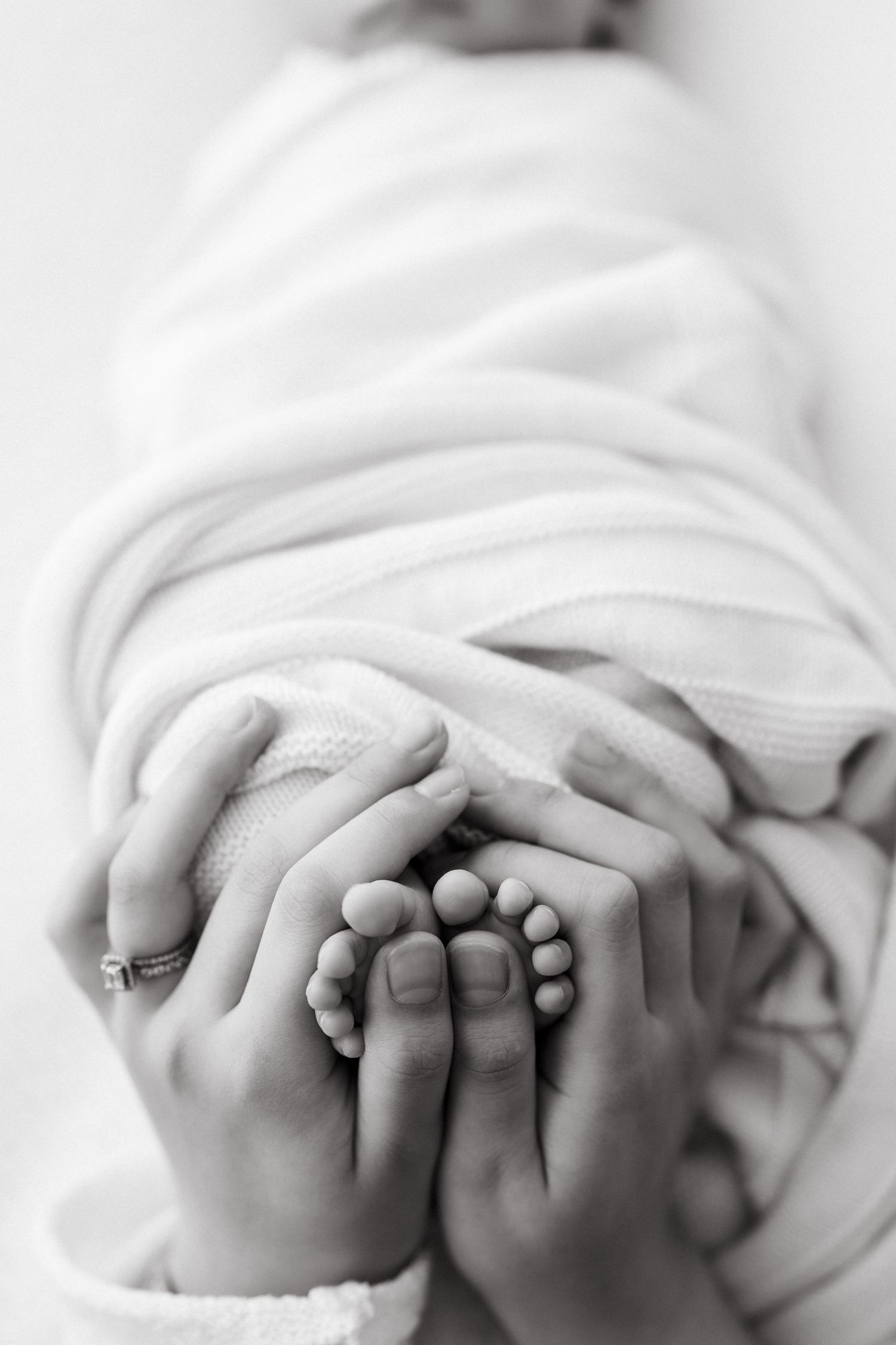 Black and white image of tiny baby feet held in adult hands.