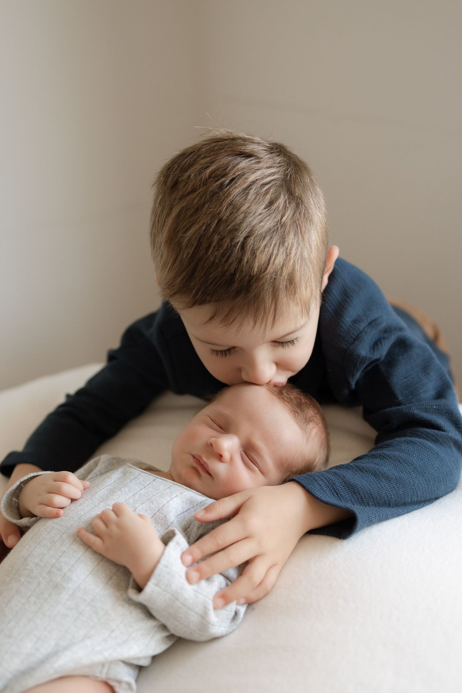 Sweet moment of siblings bonding as older child gives gentle kiss to sleeping baby.