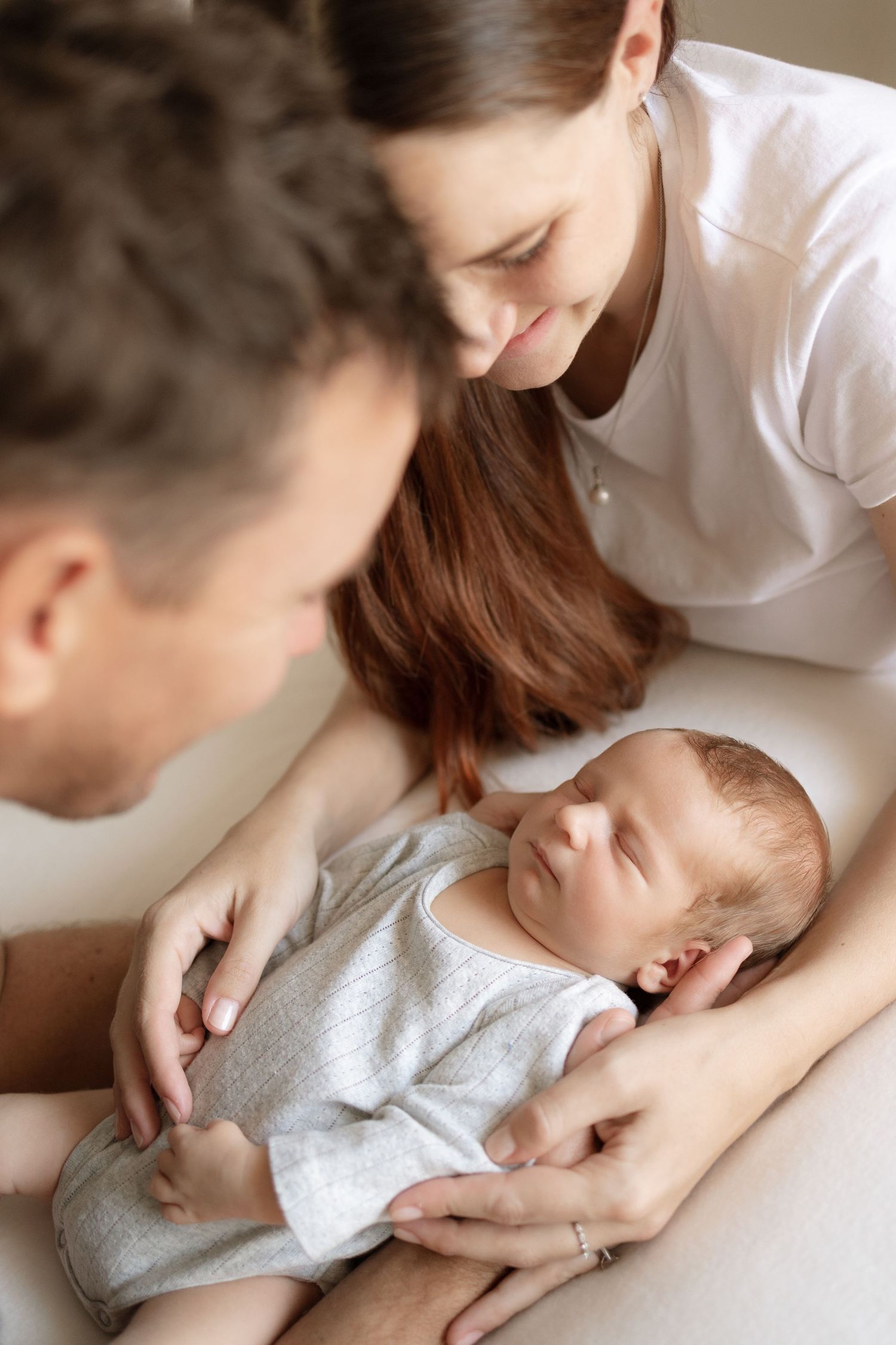 Intimate family scene with newborn baby resting between caring parents.