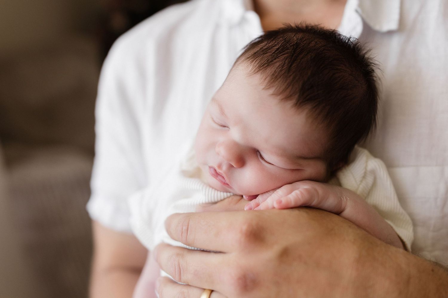 Intimate family portrait series with sleeping newborn in white.
