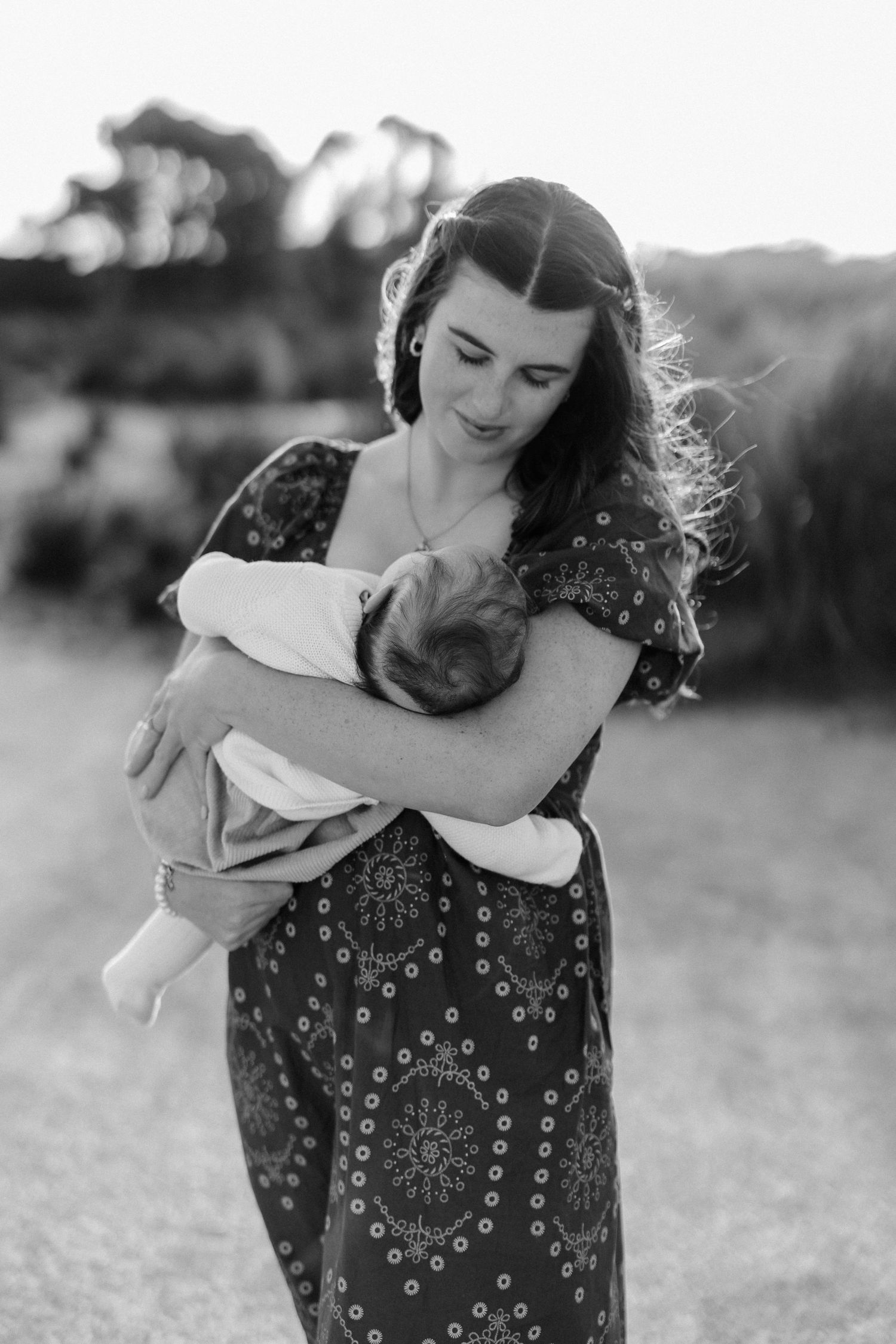 Candid black and white photo showing tender embrace in outdoor setting.