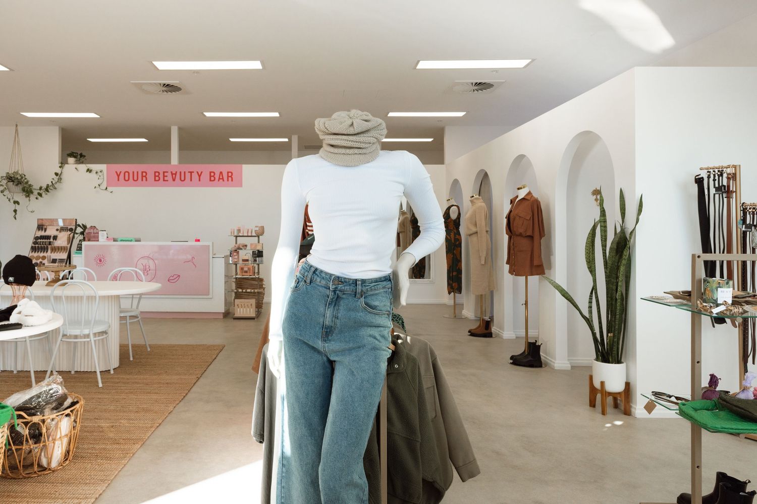 A retail clothing store interior with white walls and wooden floors displays casual apparel and accessories.