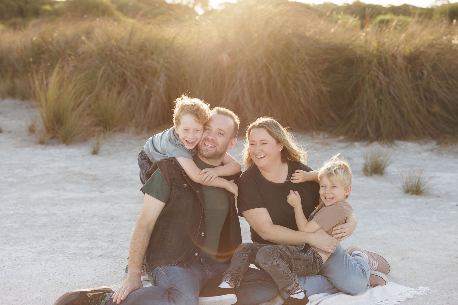 Family sharing playful moments together on beach at sunset.