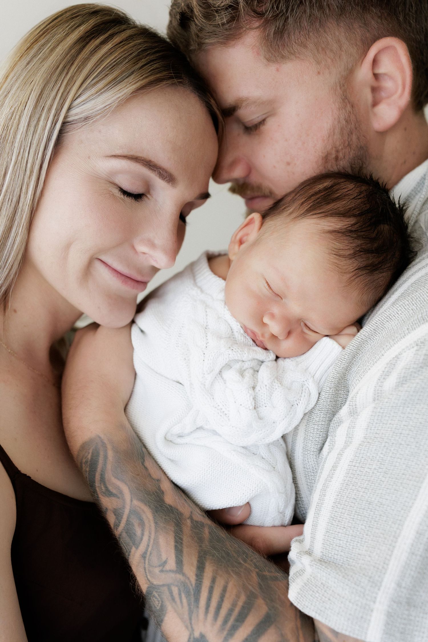 Intimate family portrait series showing tender moments with newborn.