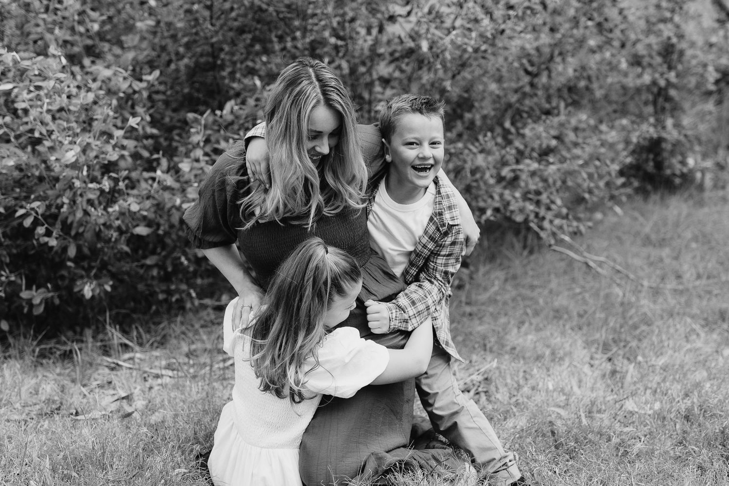 A joyful black and white photograph of a playful outdoor family moment.