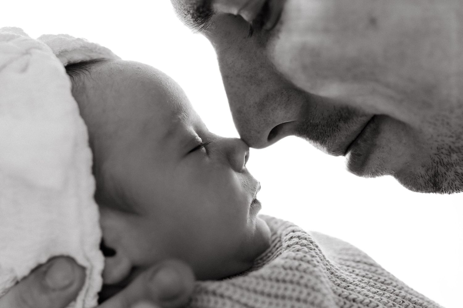 Close up black and white portrait of parent and baby in tender moment.