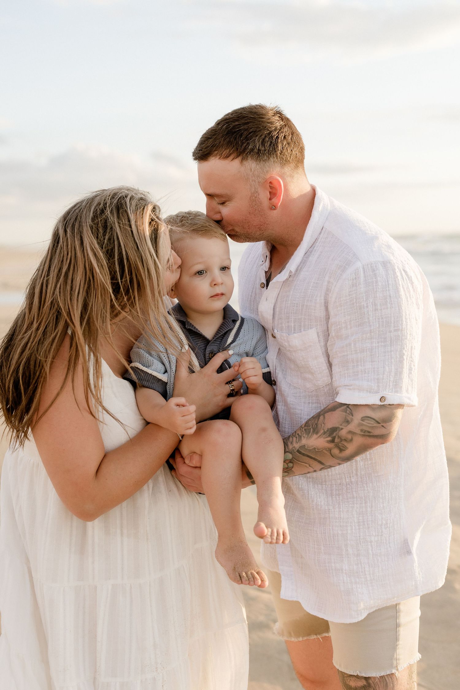 A family shares an intimate moment together on a sunny beach.