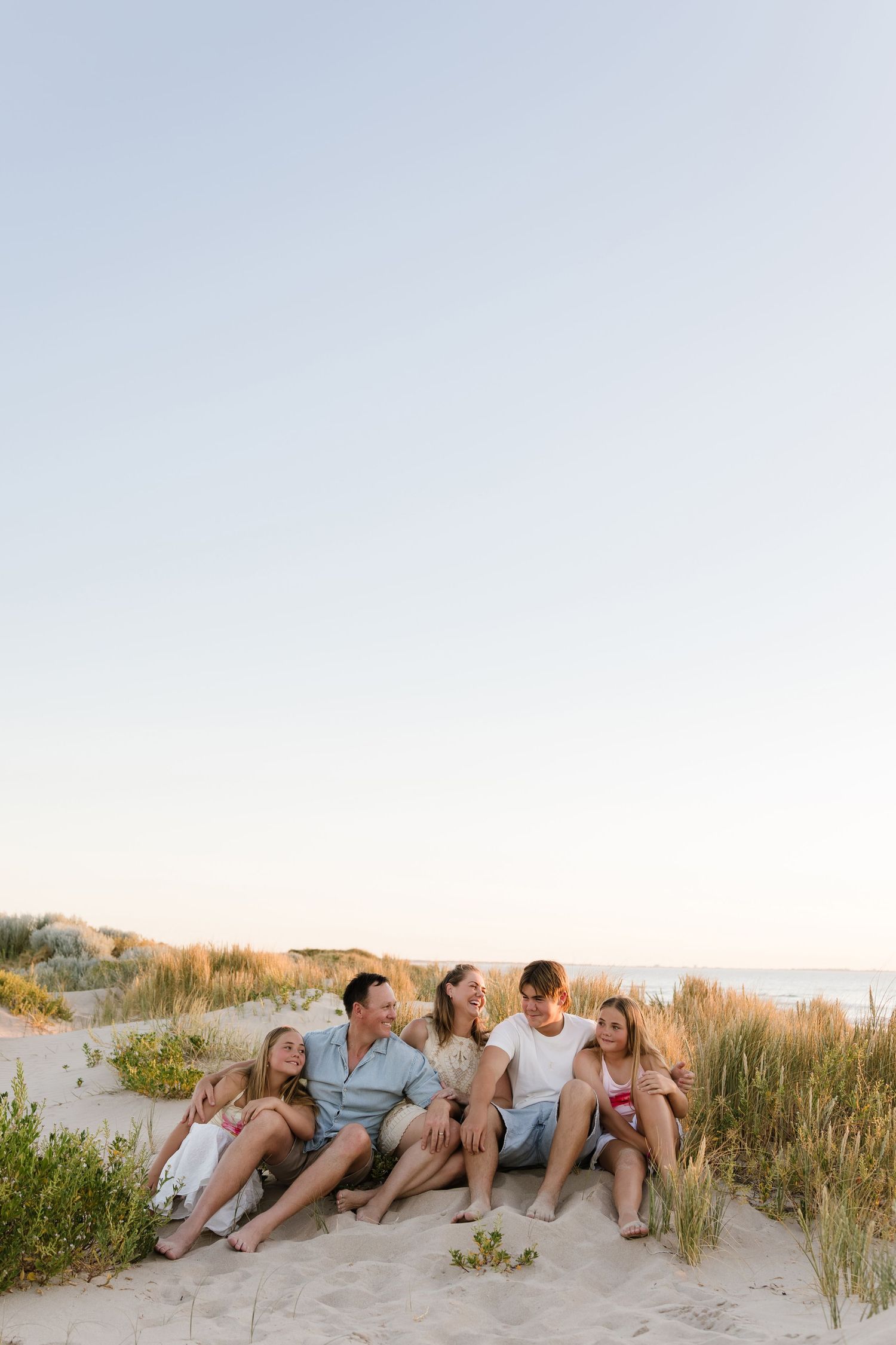 Wide angle shot of family members lounging together on a beach at sunset.