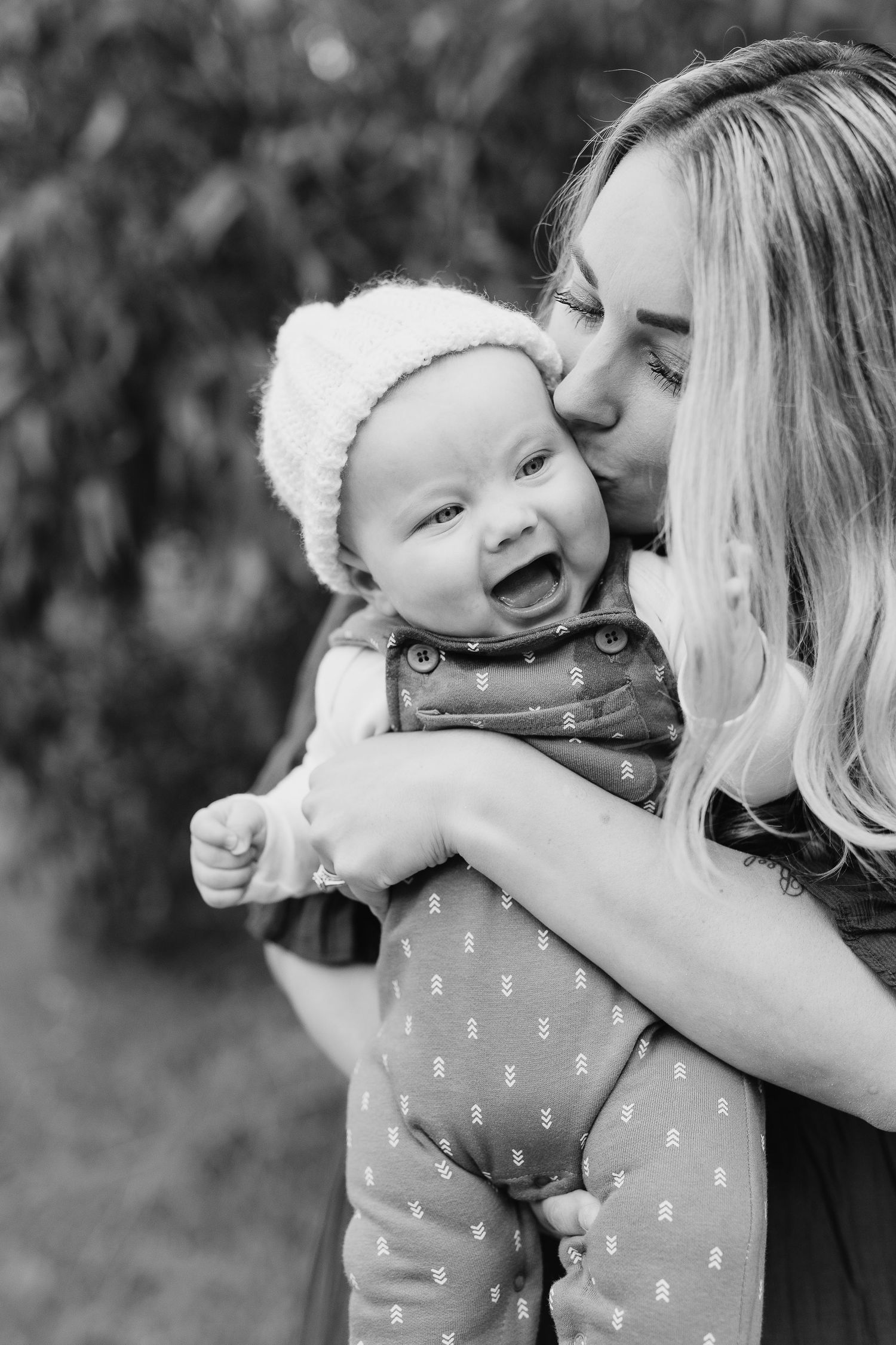 A touching black and white moment of affection and laughter captured outdoors.