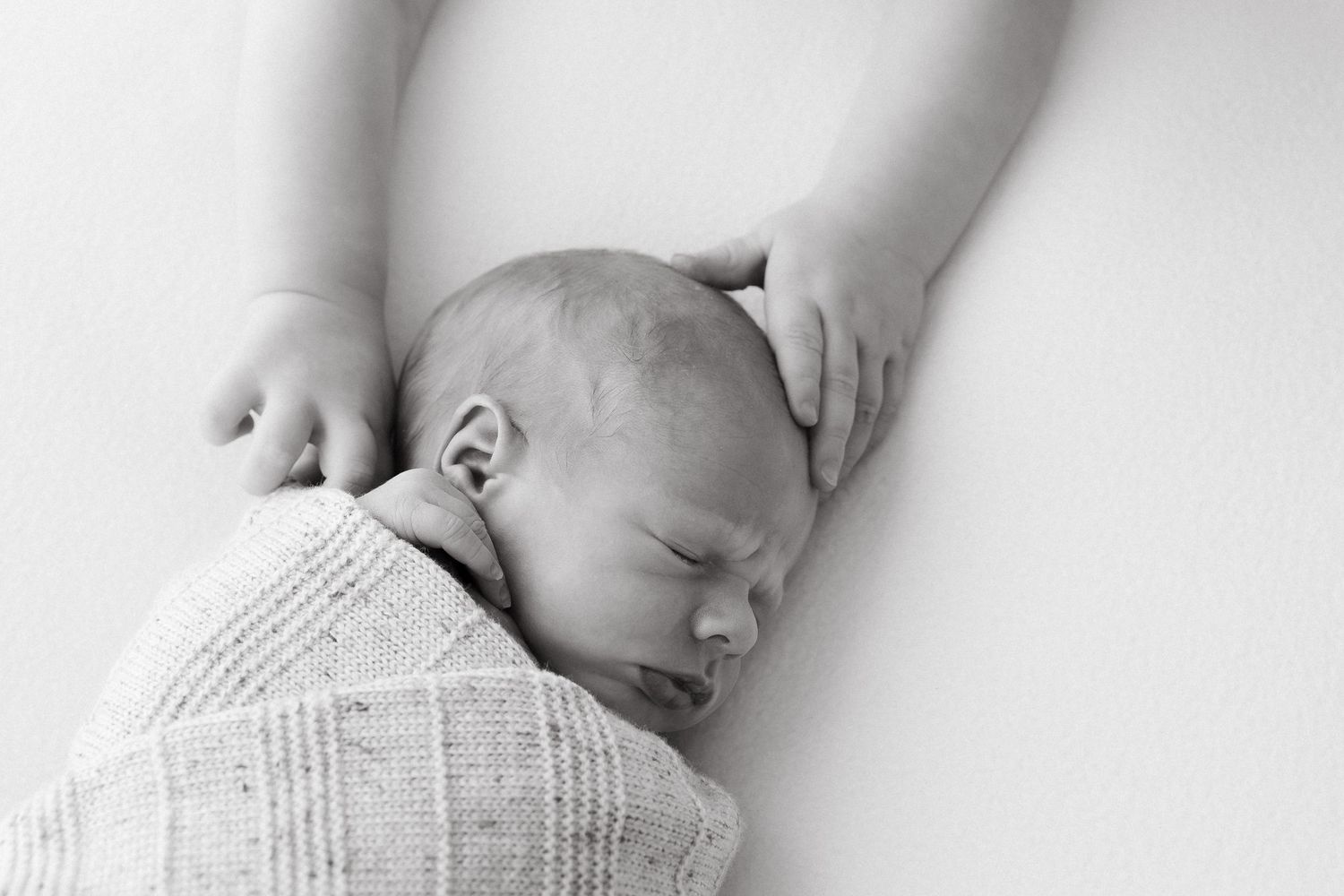 Close-up black and white images of a sleeping newborn's delicate features and tiny hands.