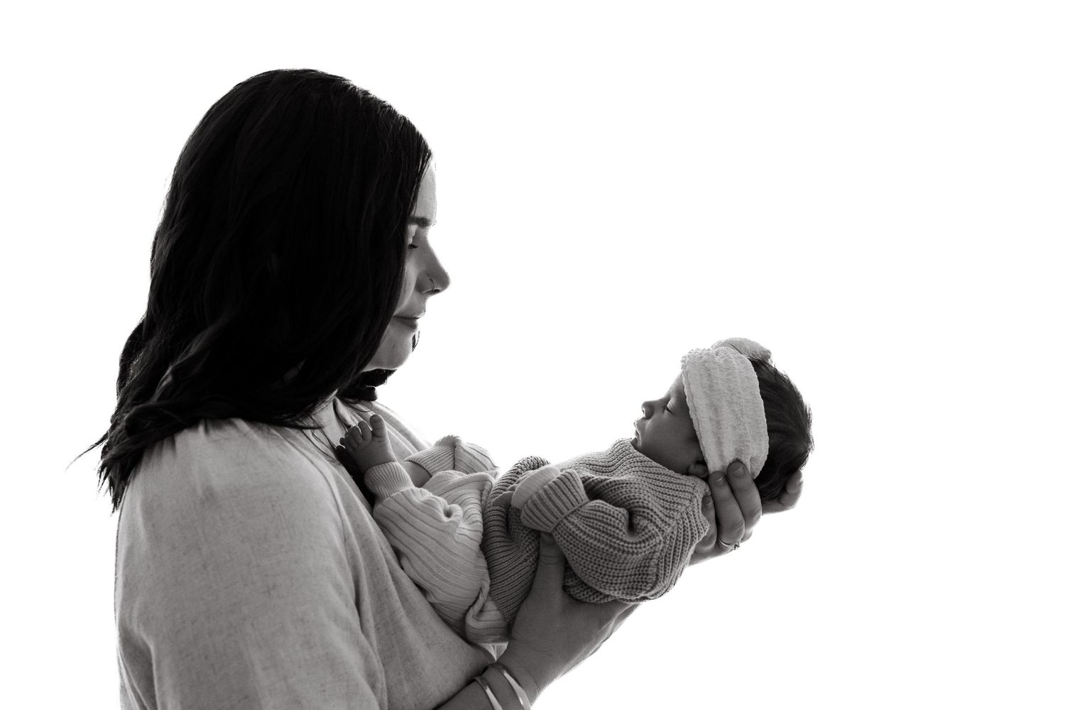 Side profile silhouette of person holding small infant in black and white.