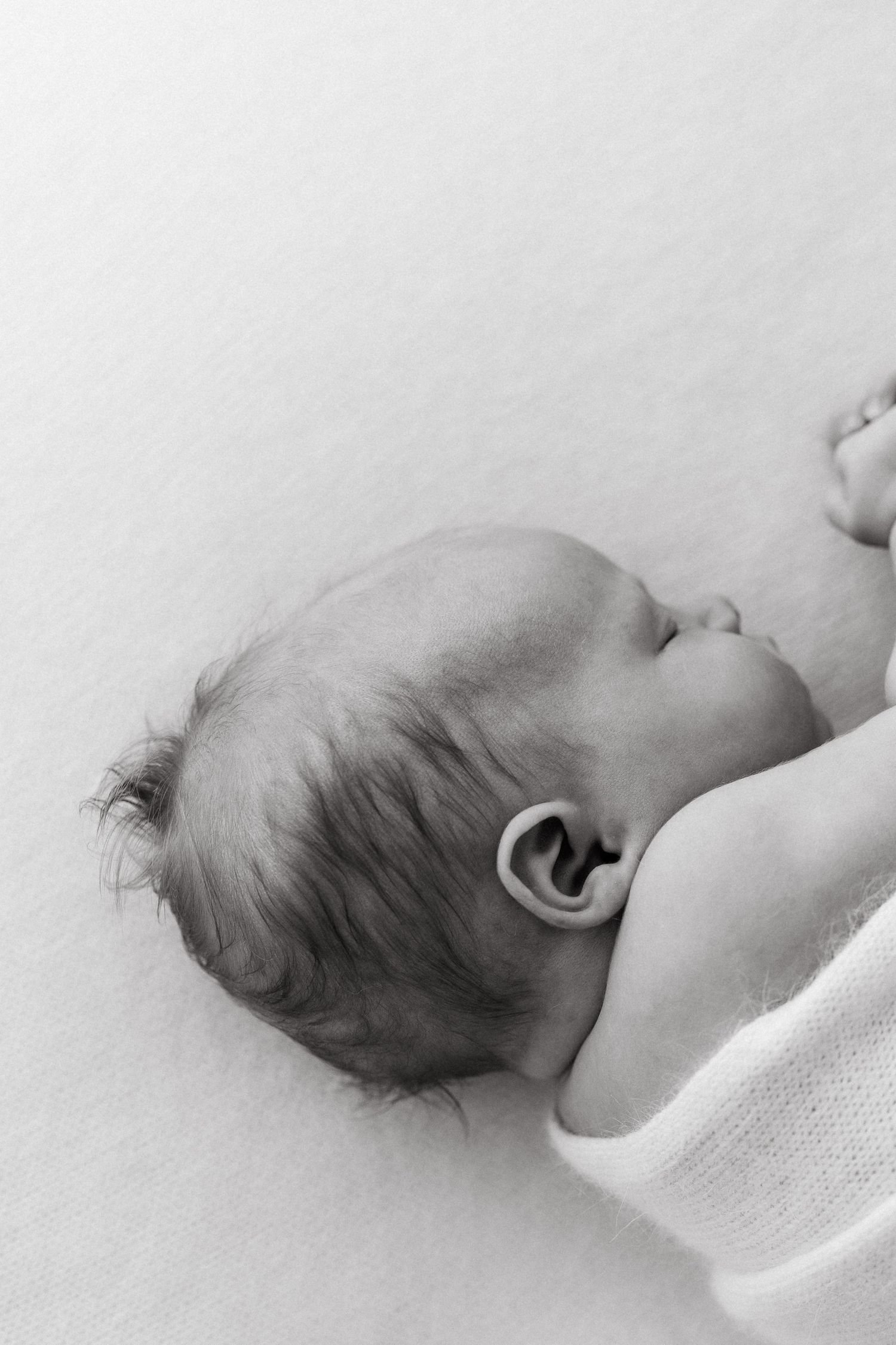 Side view of sleeping infant on white bedding in black and white.