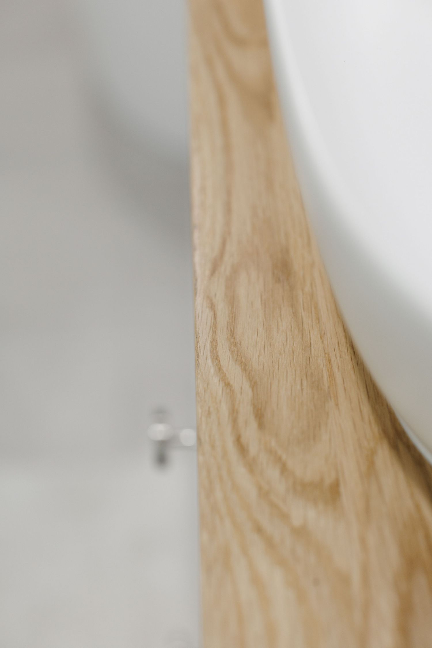 Close-up view of light wooden grain texture against a white wall with soft focus.
