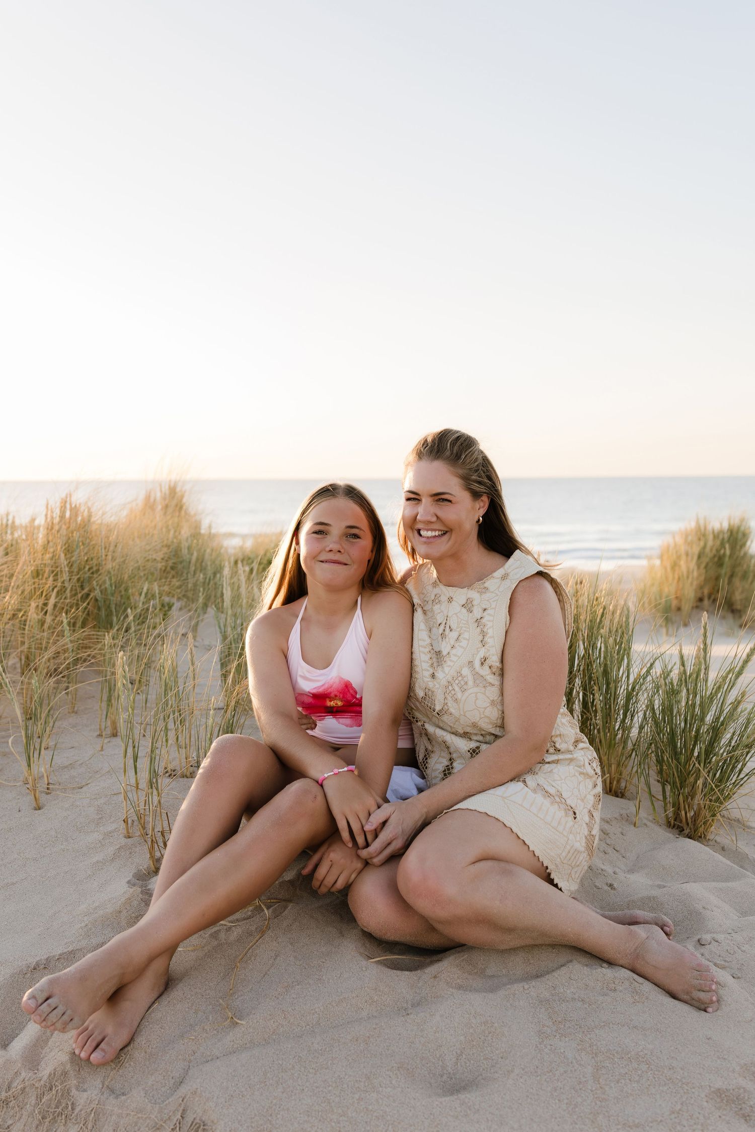 Casual beach portrait of people sitting together in the sand dunes at sunset.