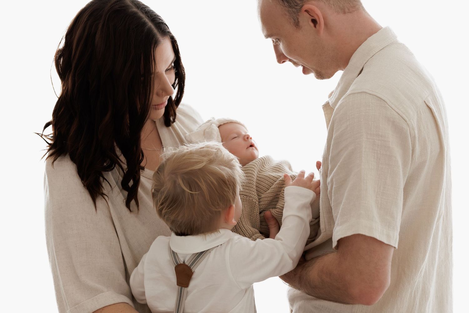 Family in white and beige clothing sharing tender moment together.