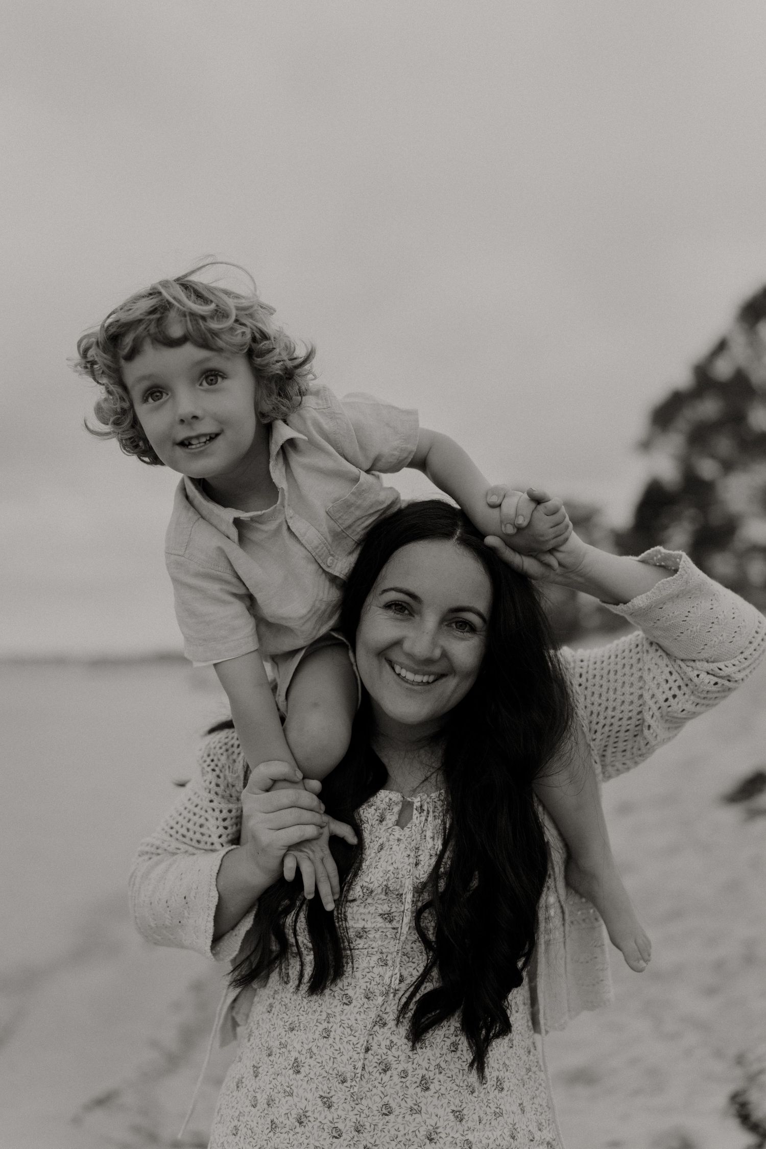 Black and white beach photos showing joyful moments between parent and child playing in the sand.