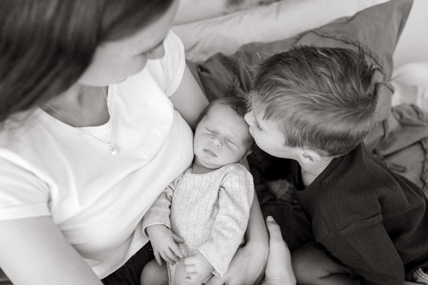 A tender black and white family moment captured on soft bedding.
