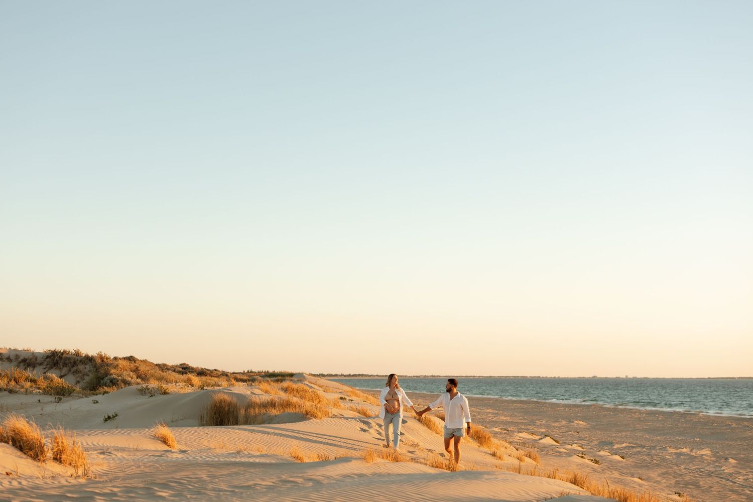 Family walking together on beach path during sunset with ocean in background.