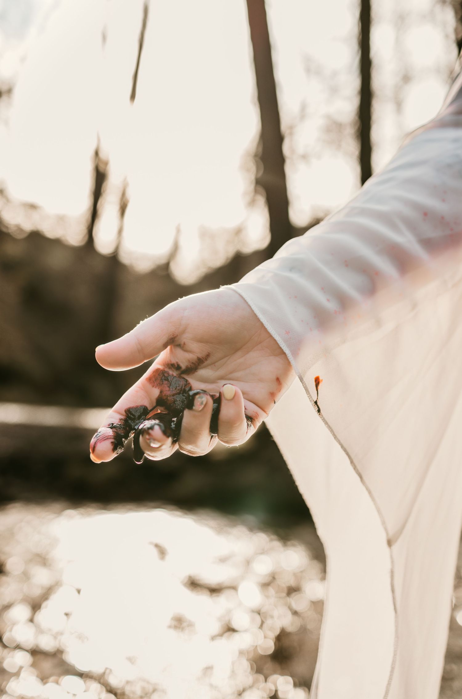 Close-up of hands in white sleeves holding vintage props against autumn forest backdrop.