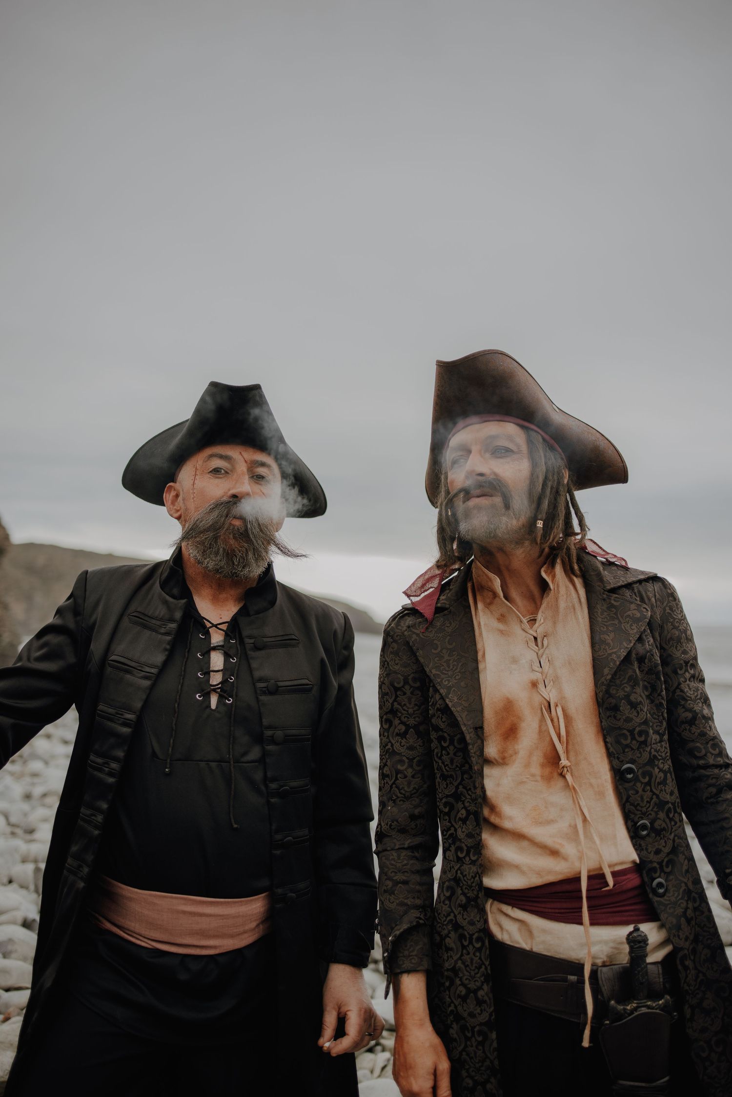 Two pirates sharing a laugh while wearing traditional 18th century costumes.