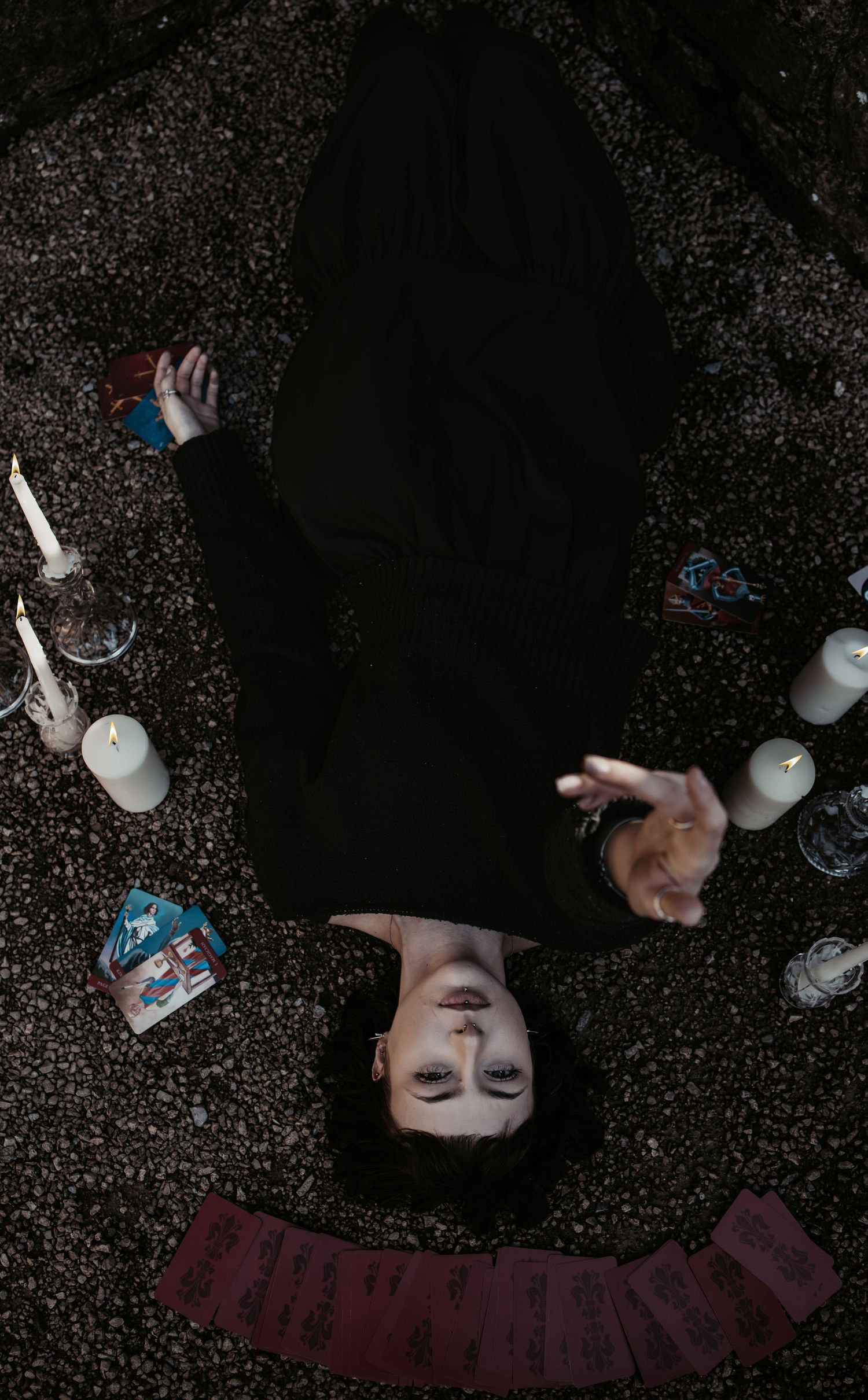 Overhead dark artistic portrait with scattered candles creating ambient lighting.