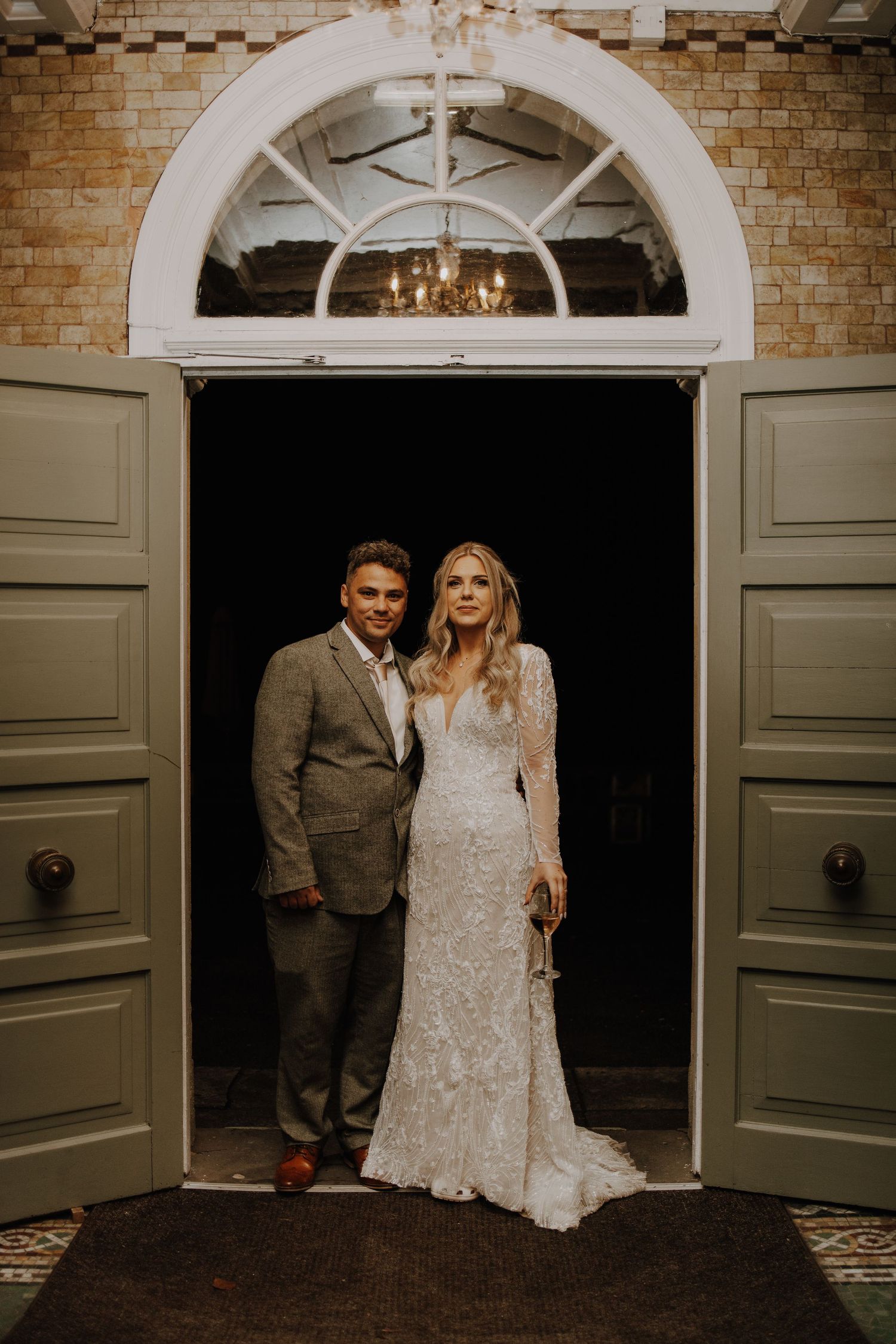 Elegant wedding venue entrance with large green doors and arched transom windows.