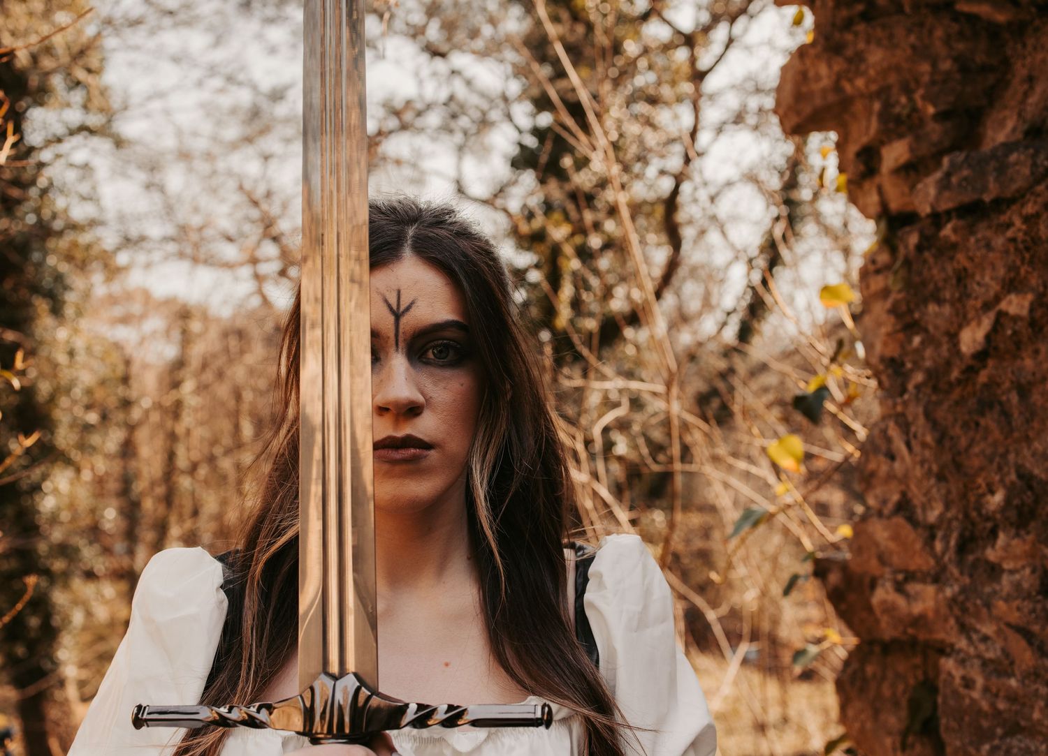 Autumn forest portrait with renaissance-inspired costume and dramatic lighting.
