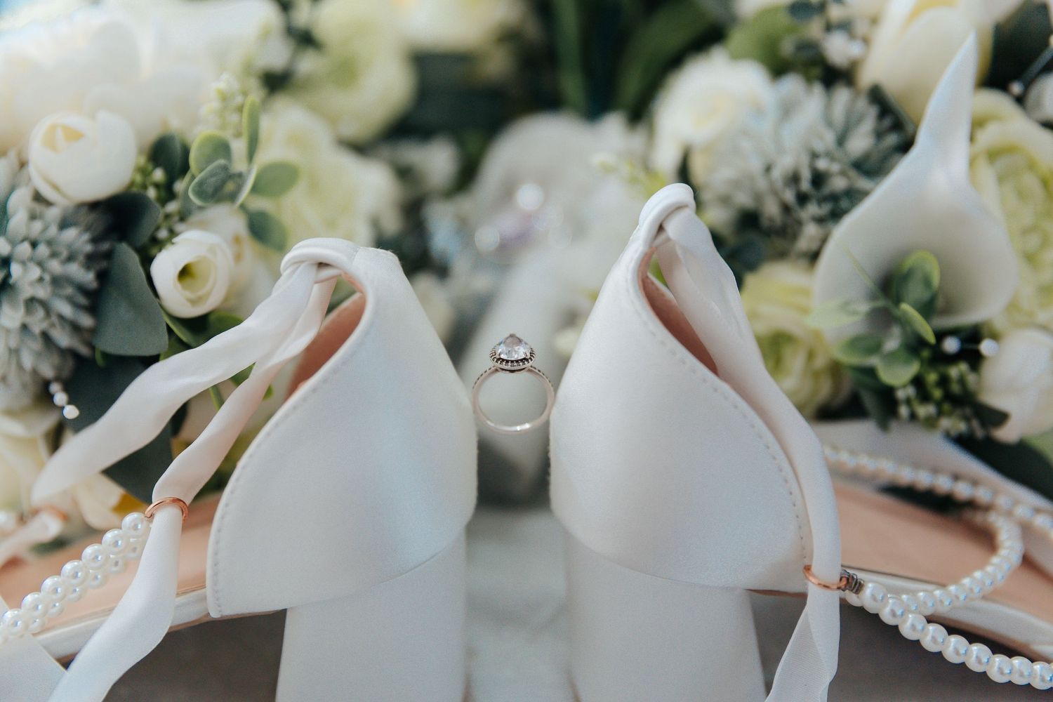 Elegant white bridal shoes and accessories arranged on a soft neutral background.