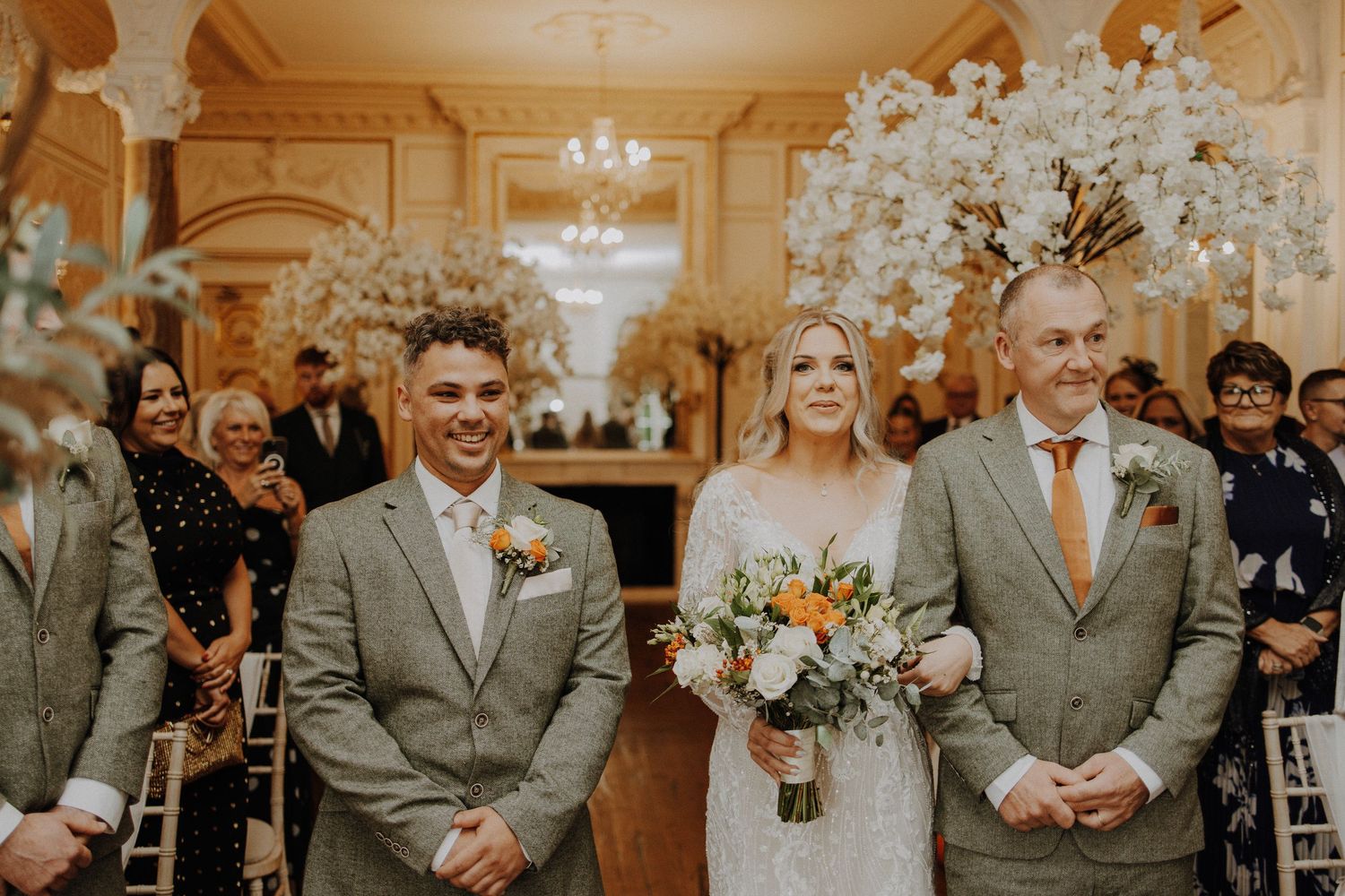 Wedding party members in gray suits standing together during formal portraits.