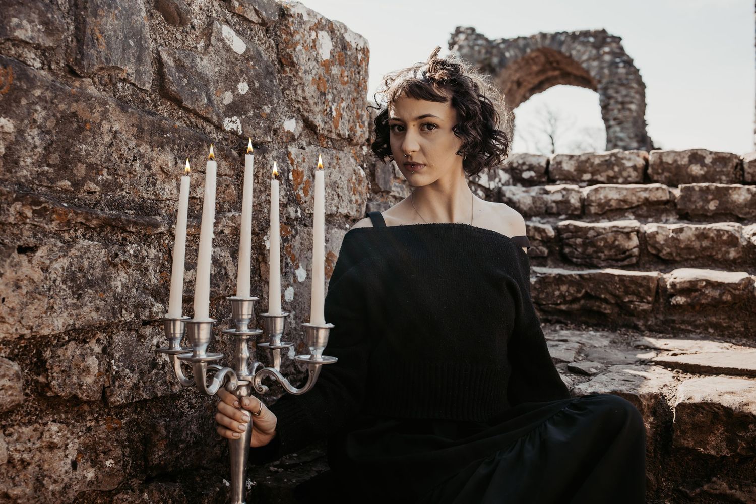 Candlelit scene with gothic elements against weathered stone architecture.