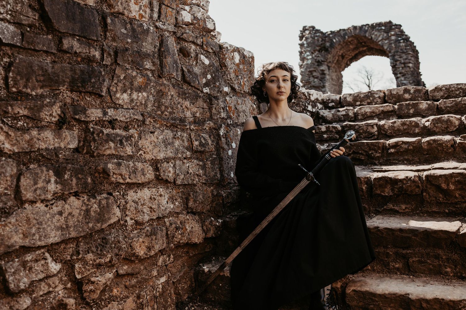 Stone castle ruins provide backdrop for dramatic medieval-themed portrait.