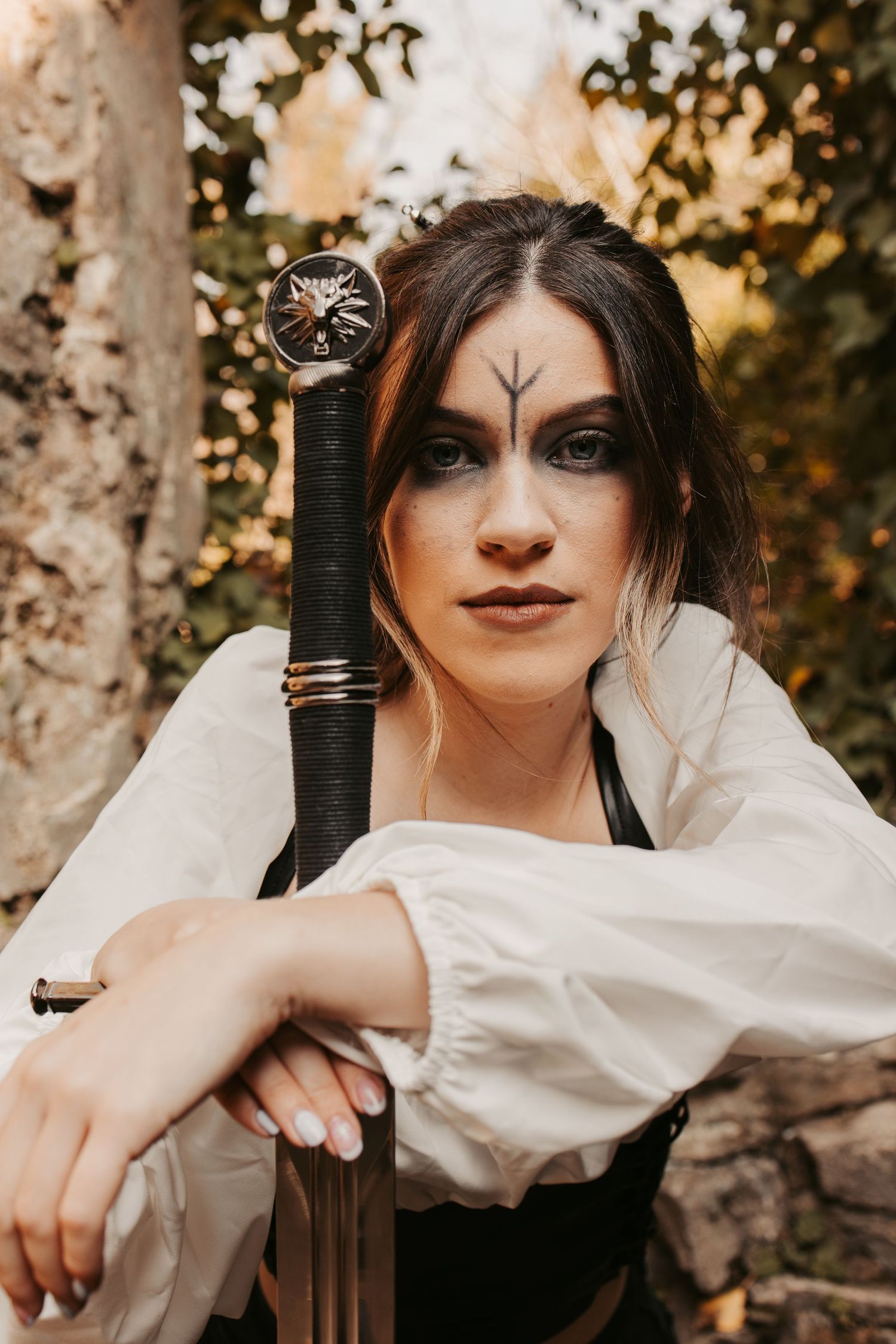 Medieval-themed portrait with sword and renaissance costume against natural backdrop.