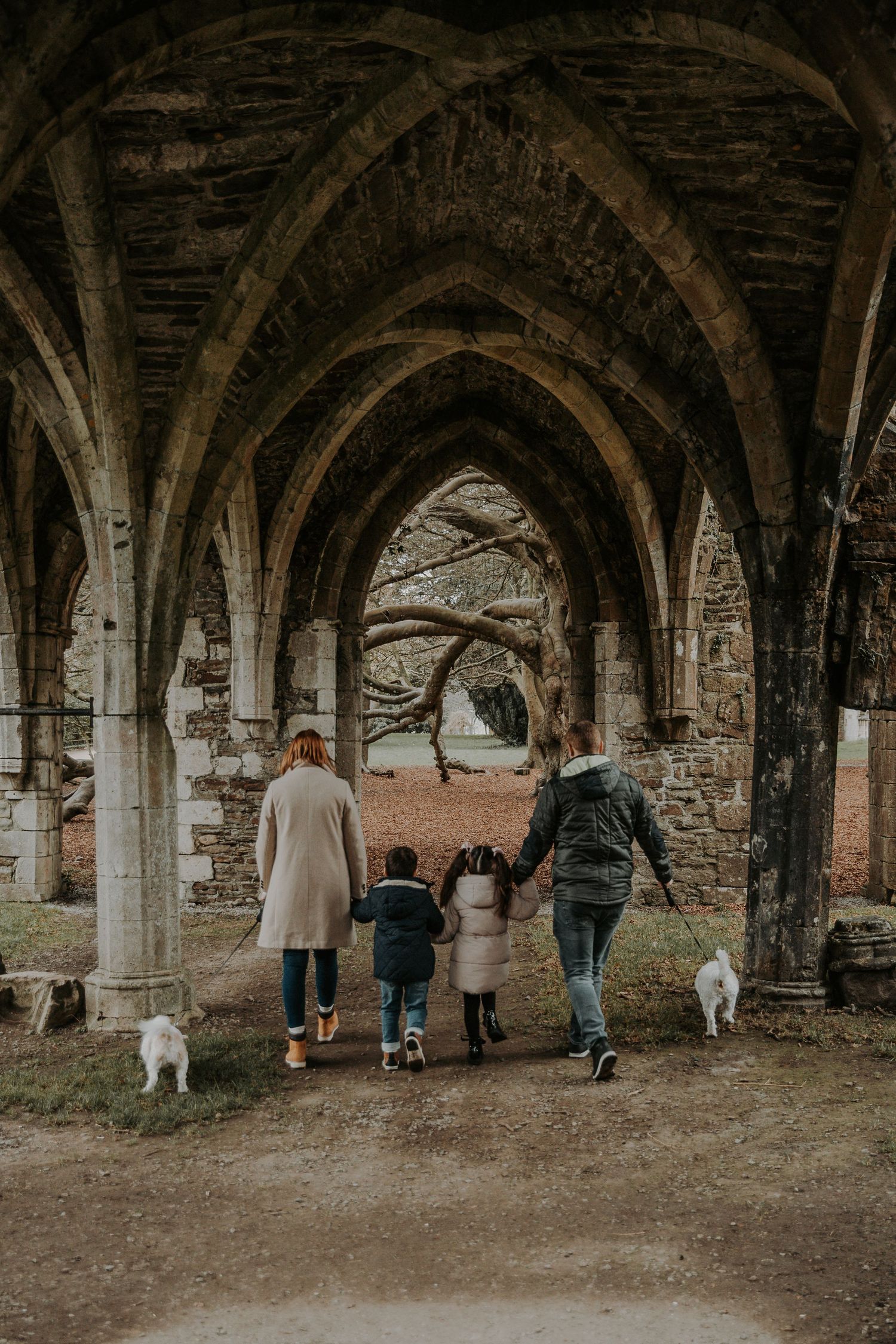 Group walking through historic stone archways in an atmospheric underground passage.