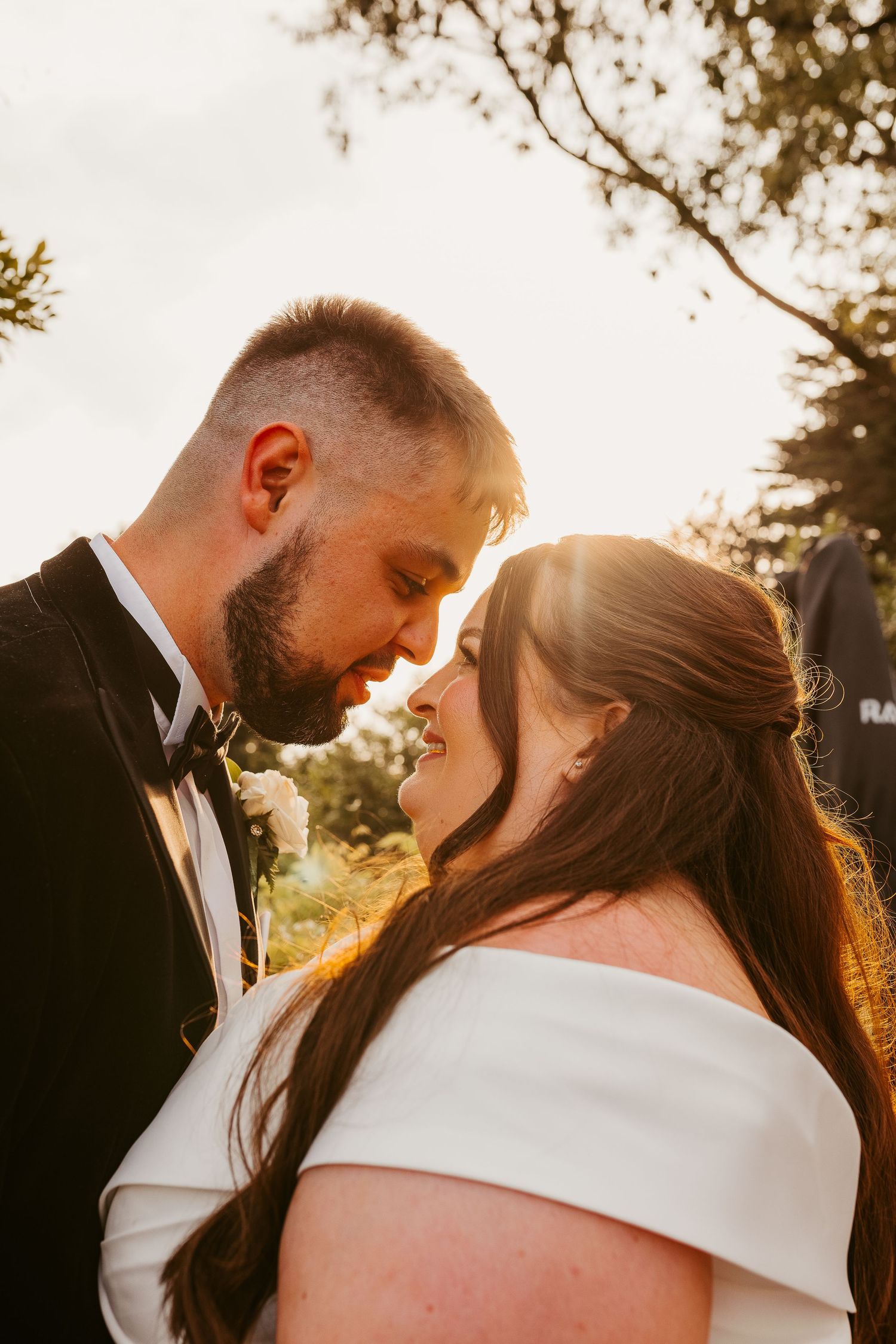 Romantic sunset wedding portrait of couple sharing an intimate moment in golden light.