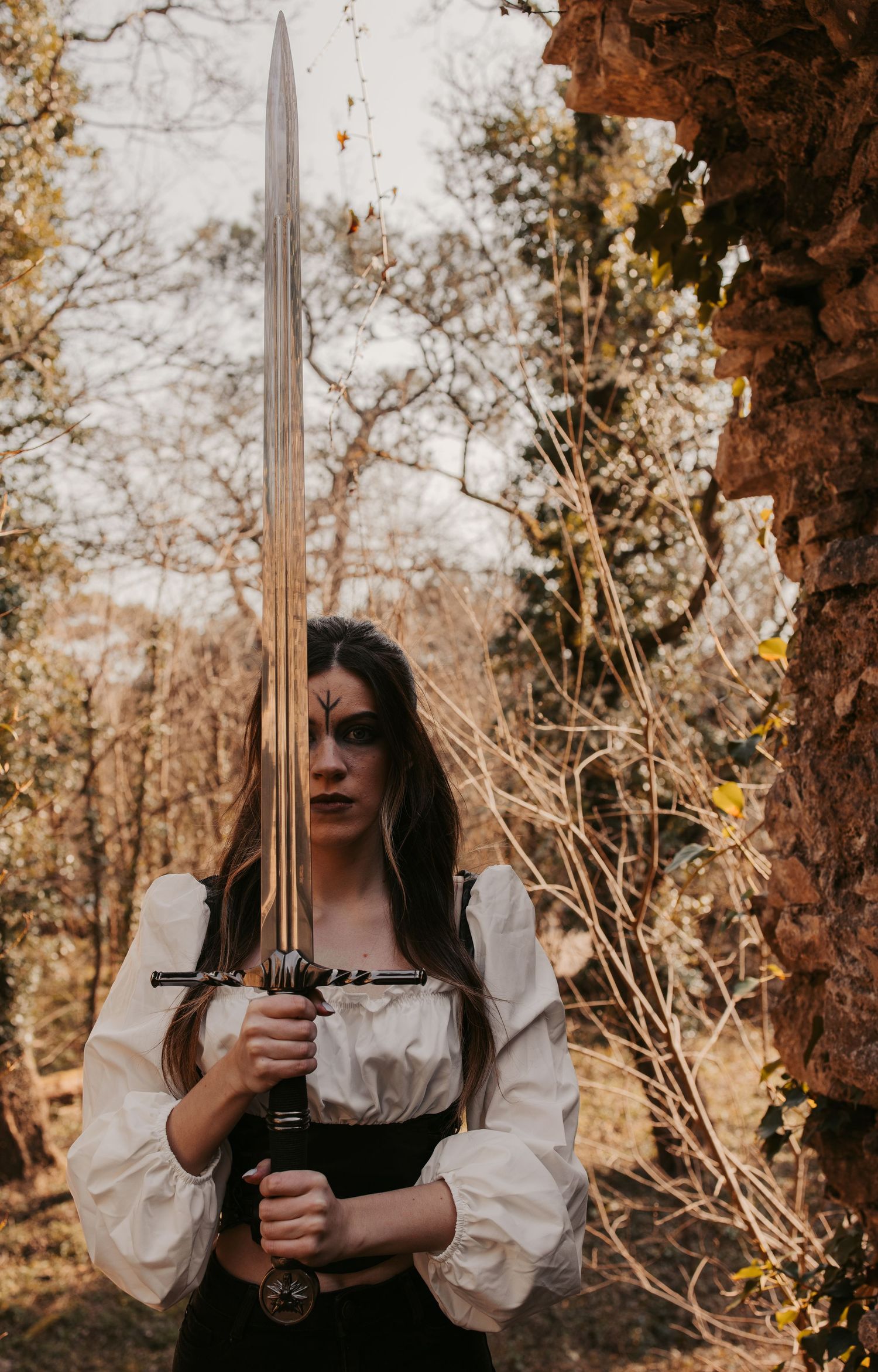 Medieval-inspired portrait with sword and flowing white sleeves against autumn backdrop.