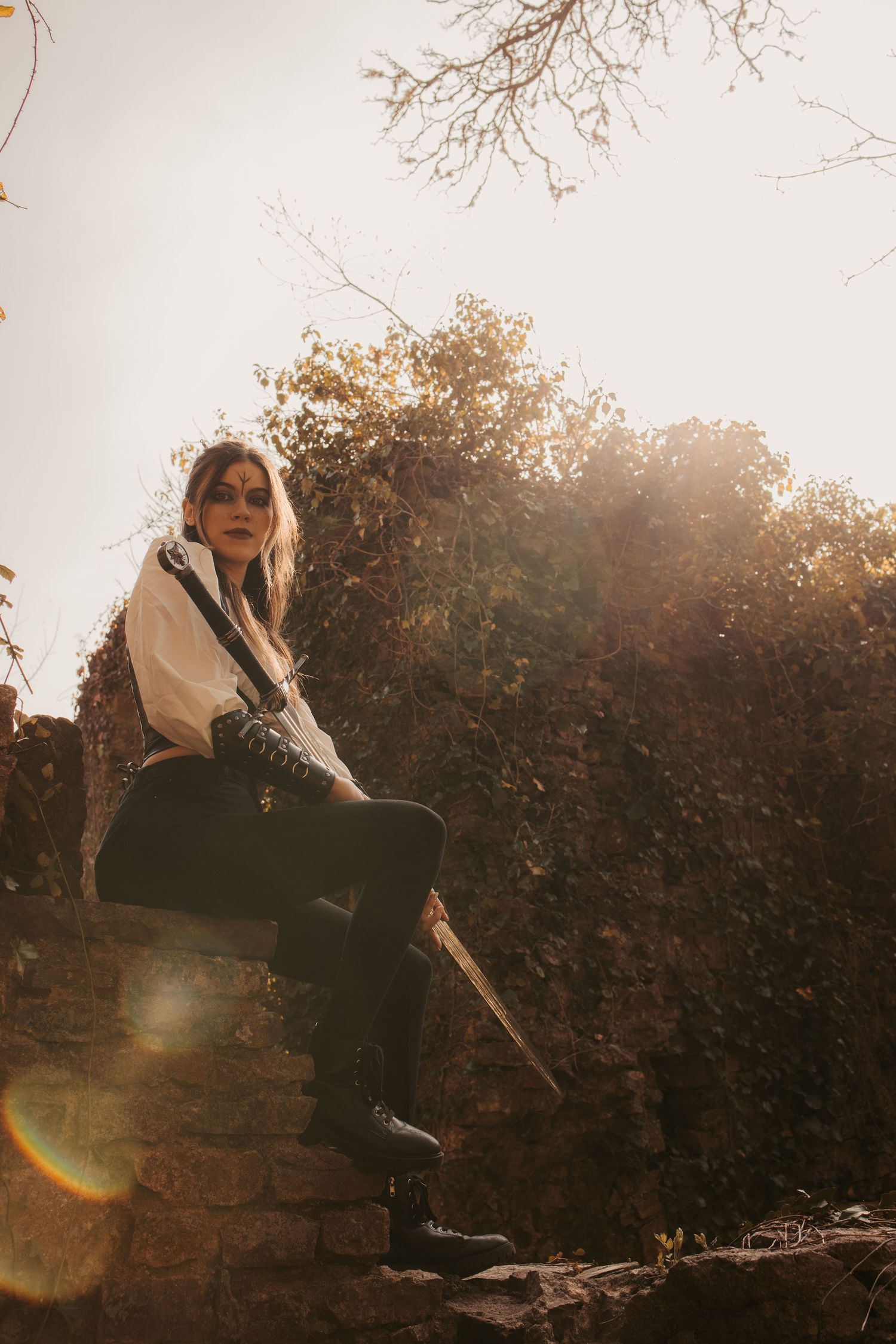 Figure perched on stone wall during golden hour with dramatic lighting.