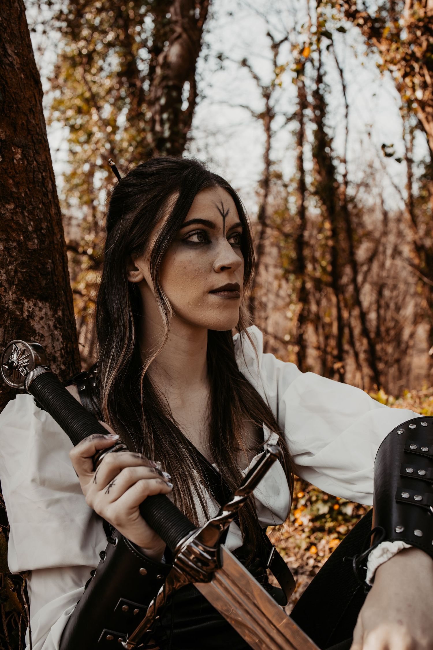 Atmospheric autumn forest scene with period costume and prop weapons.