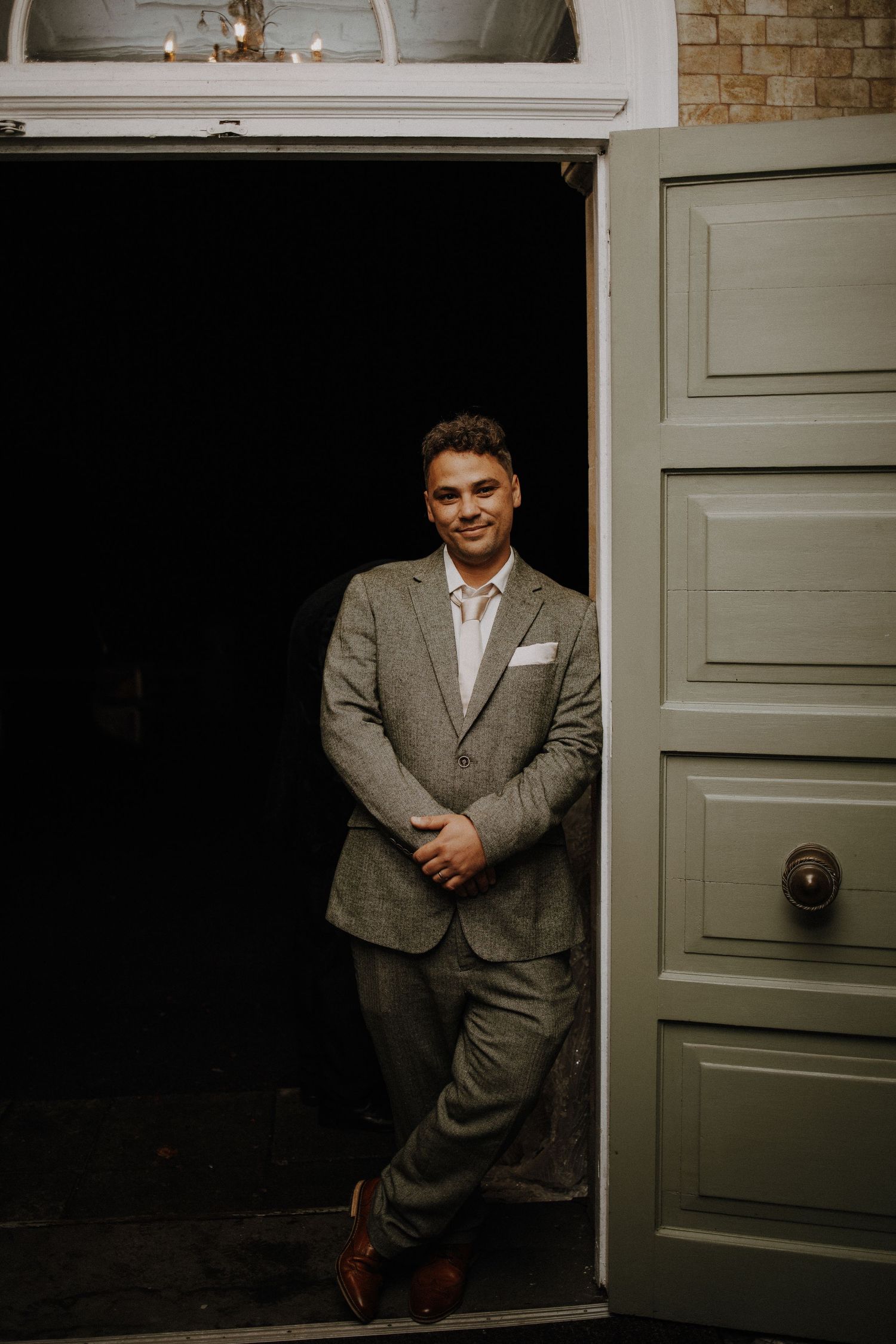 Dramatic portrait against gray doors in moody lighting.