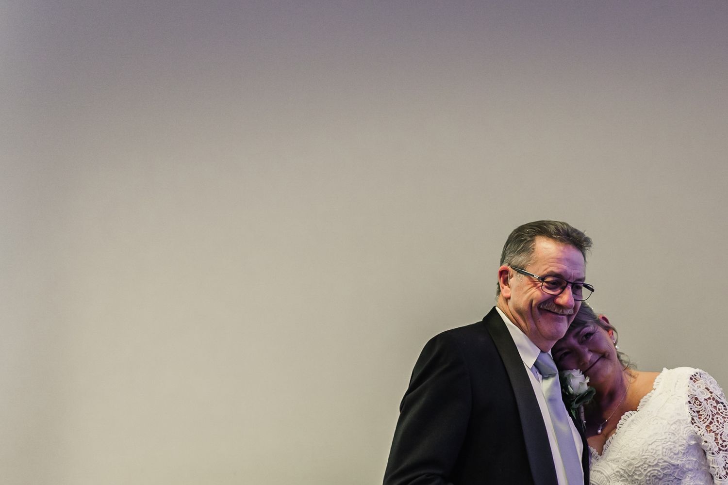 Indoor wedding portrait session against neutral background capturing intimate moments.