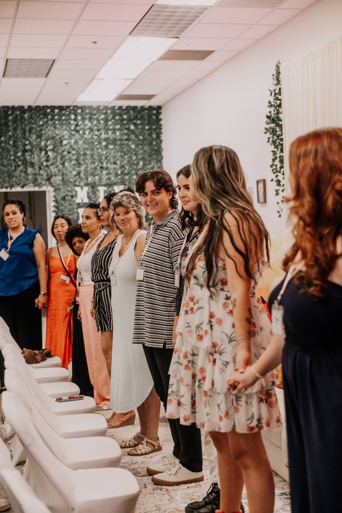 A group of attendees stand in a line inside a decorated event space.