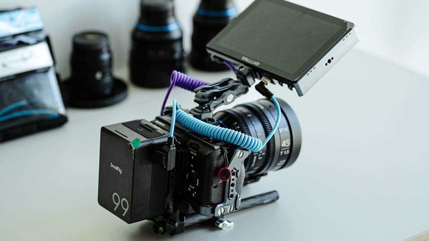 A professional cinema camera rig with monitor, follow focus, and prime lenses on a white surface.