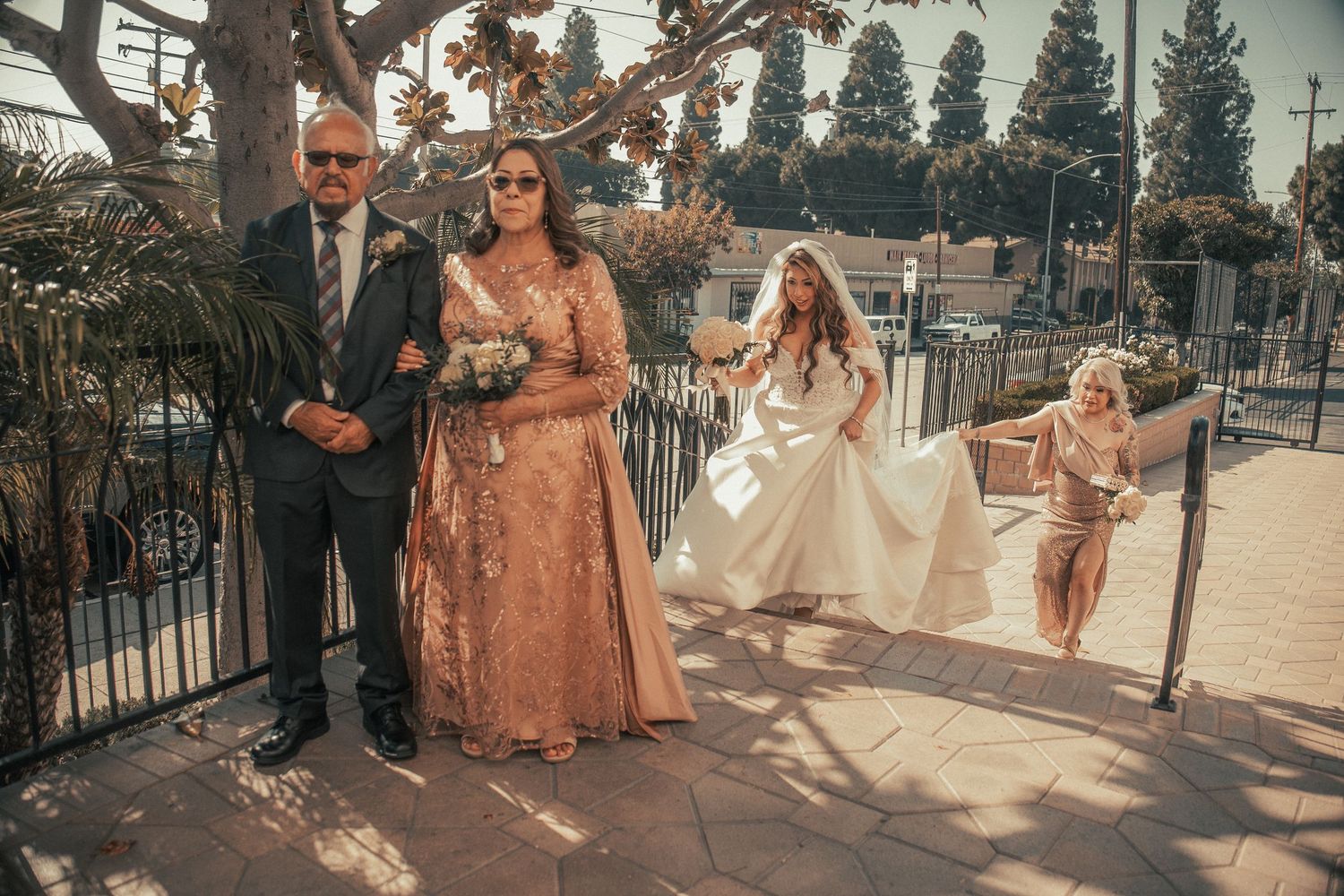 Bride in white gown with family members in formal attire gathered outside a church before the wedding ceremony.