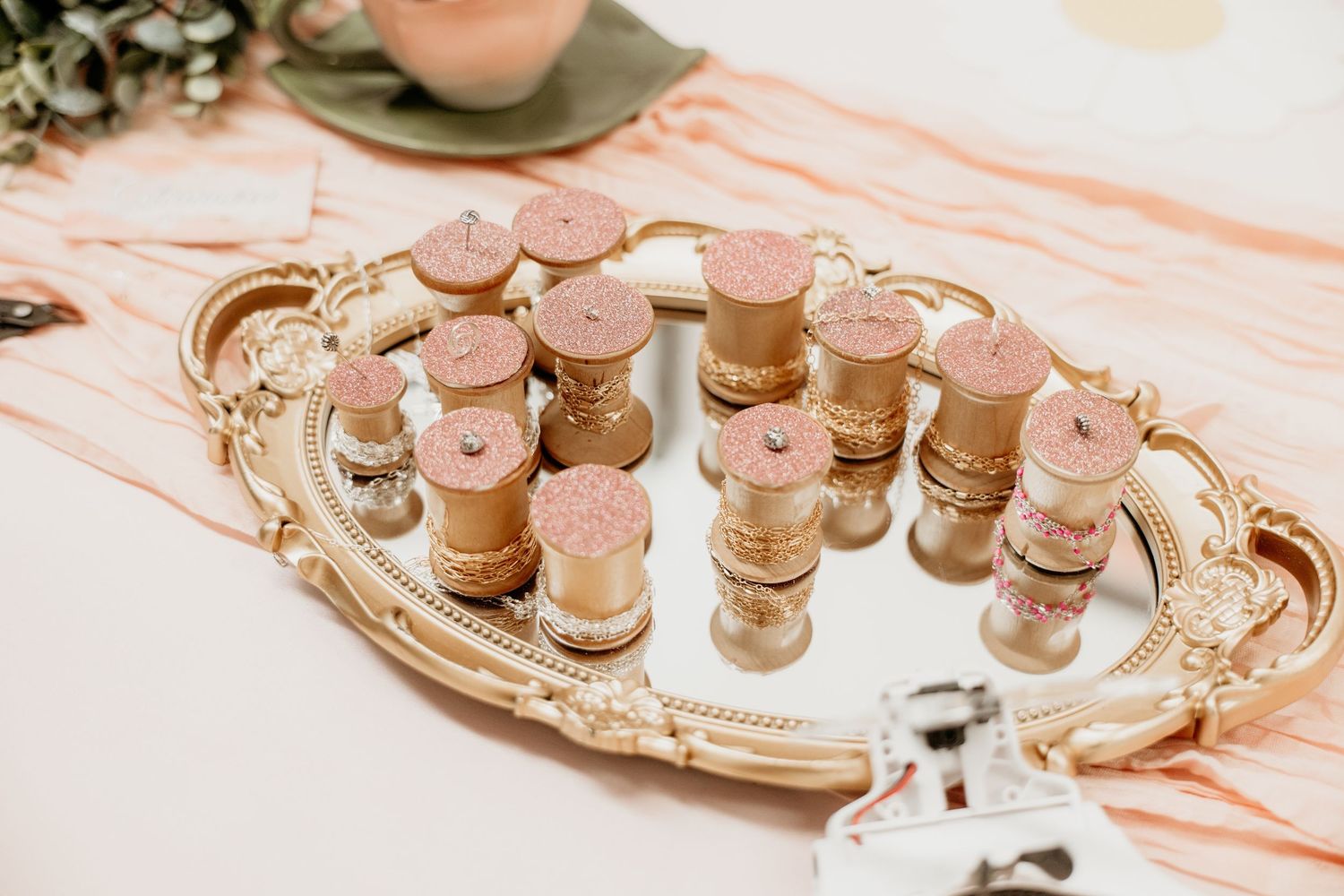 Small cork-topped glass jars with glitter displayed on a gold mirrored tray.