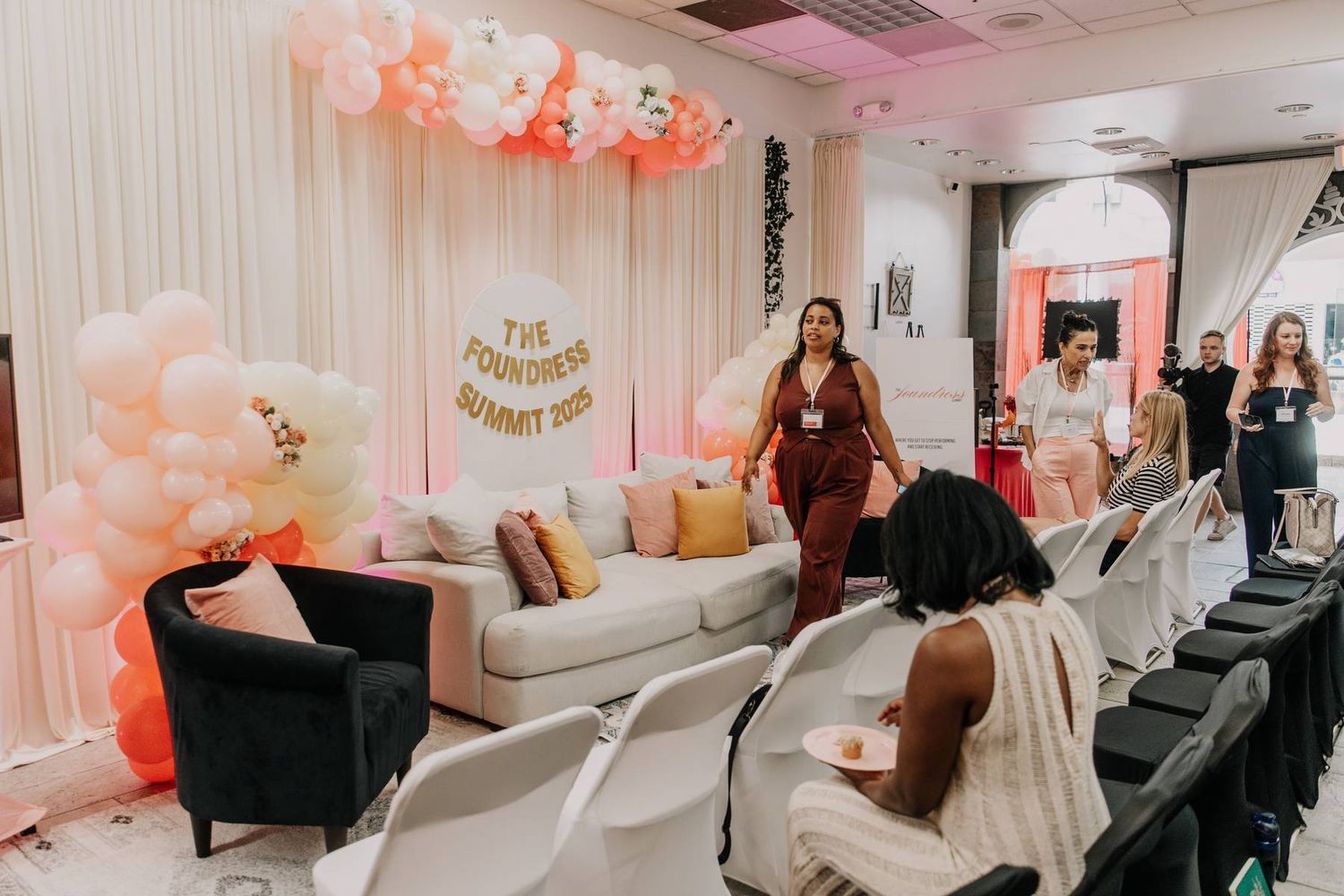 Guests mingle at The Founders Summit 2023 event with pink balloon decor.