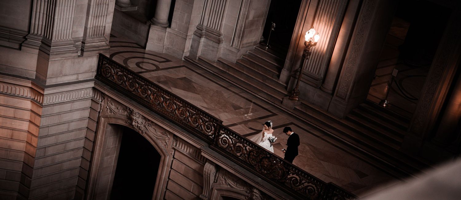 Couple sharing a romantic moment on an ornate balcony inside a grand historic building.