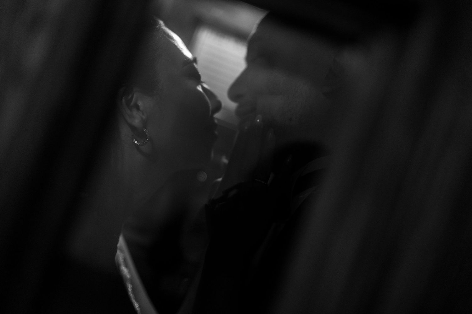 Black and white romantic couple kissing in soft bokeh light, intimate love portrait photography.