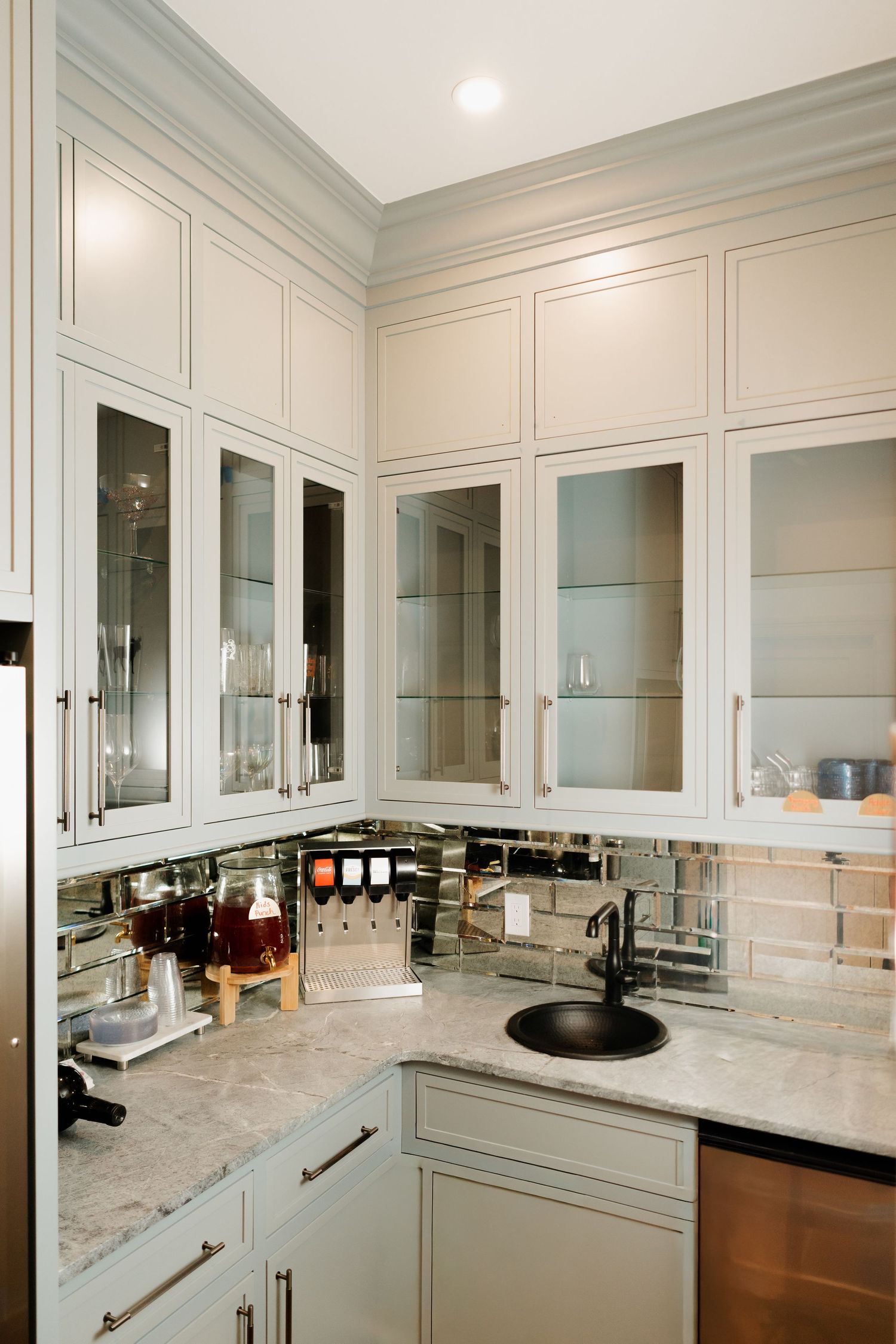 High-end kitchen featuring glass-front cabinets, marble countertops, and mirrored backsplash.