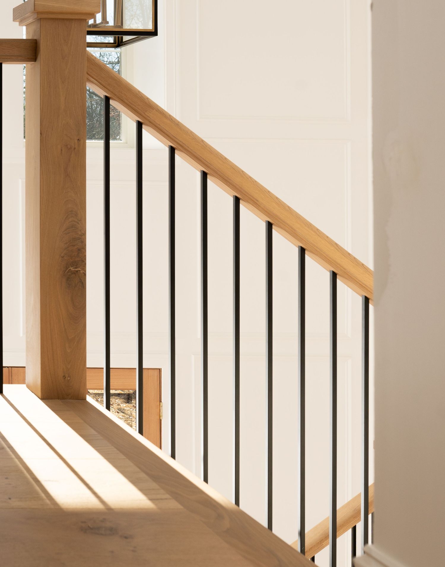 Modern staircase design featuring wooden handrails and black metal spindles in a minimalist style.