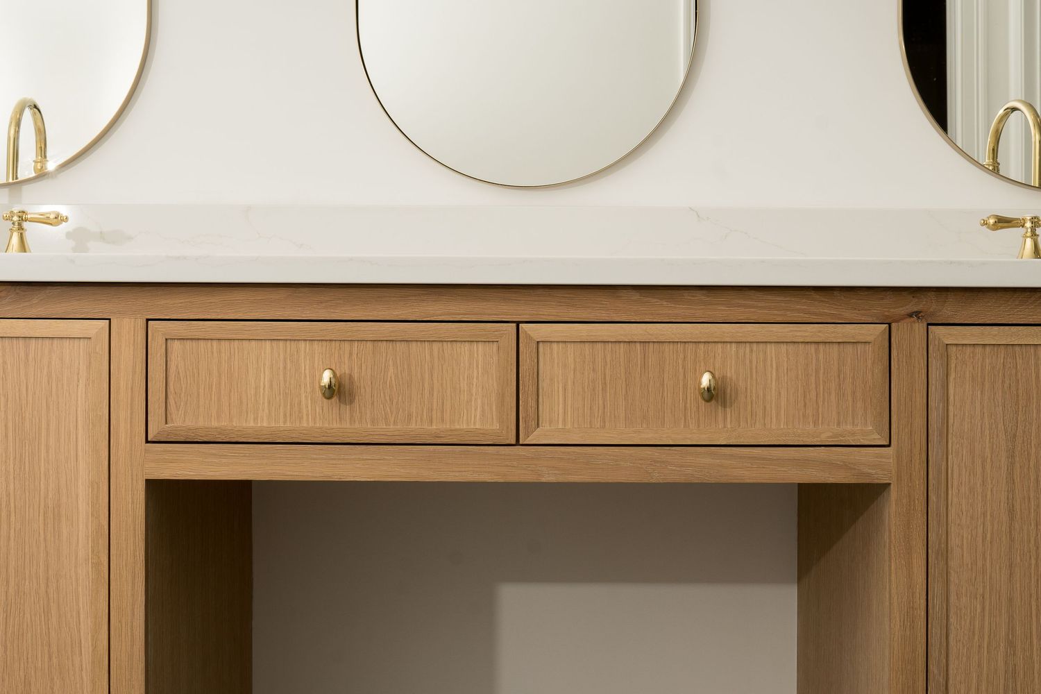 Built-in bathroom vanity with round mirrors and warm wood cabinetry provides elegant storage solutions.